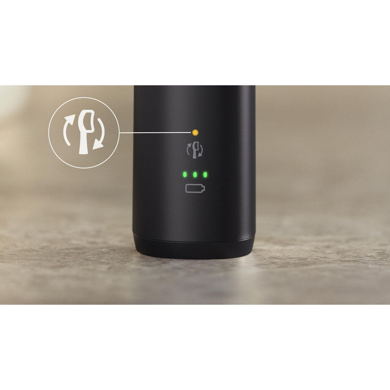 Un appareil noir avec des voyants de batterie et une icône. Le fond est une table.