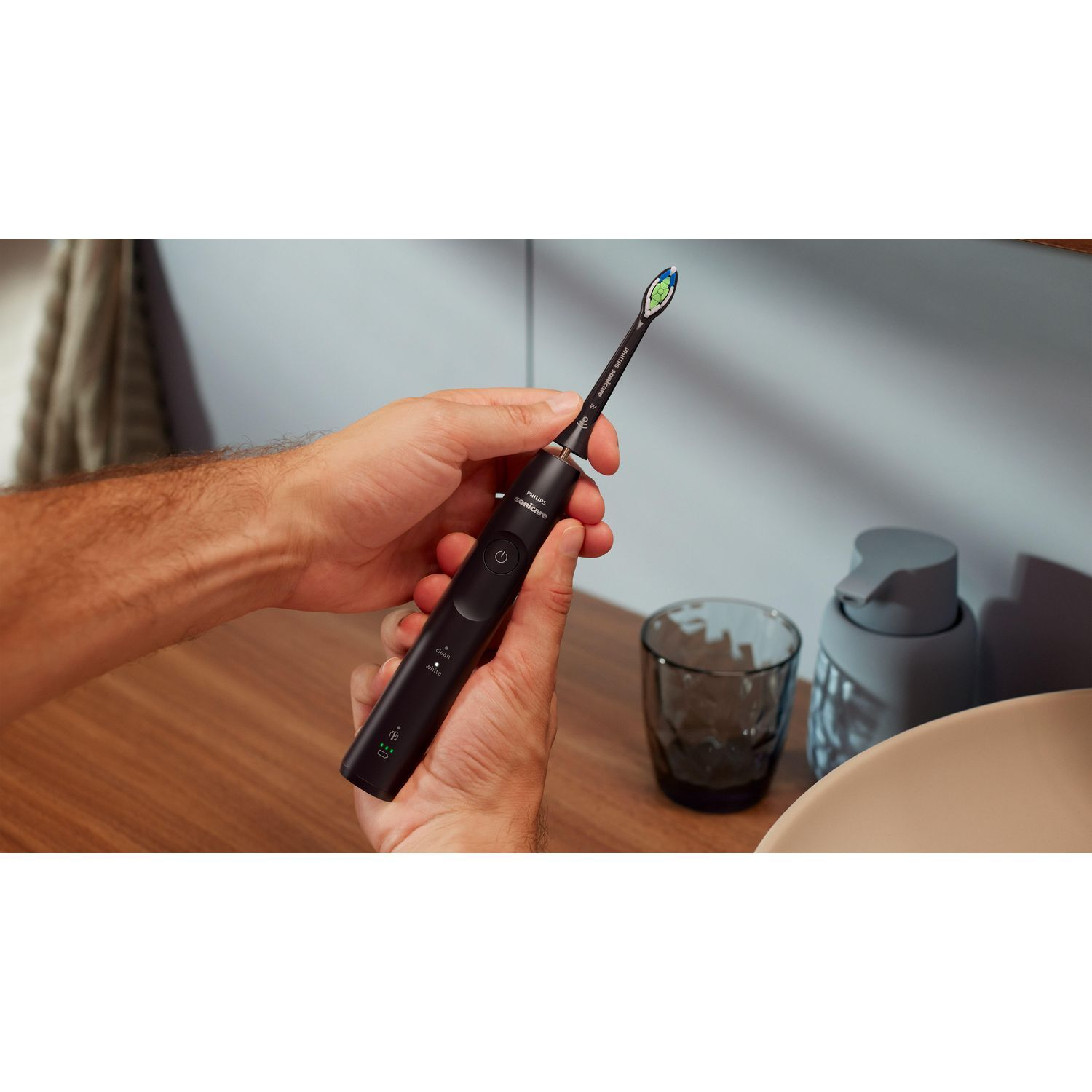 Person holding a black Philips Sonicare toothbrush. The toothbrush has a black handle and a brush head.