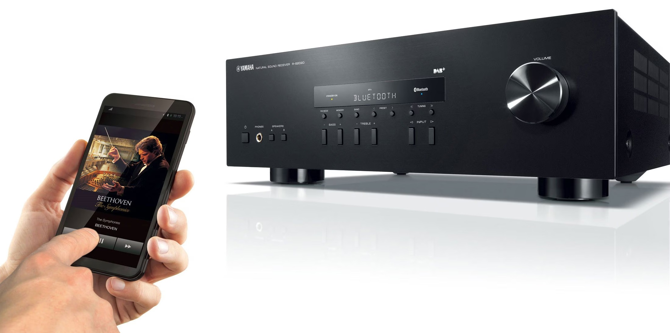 Czarny odbiornik stereo obok smartfona z Beethovenem, ręka na ekranie.