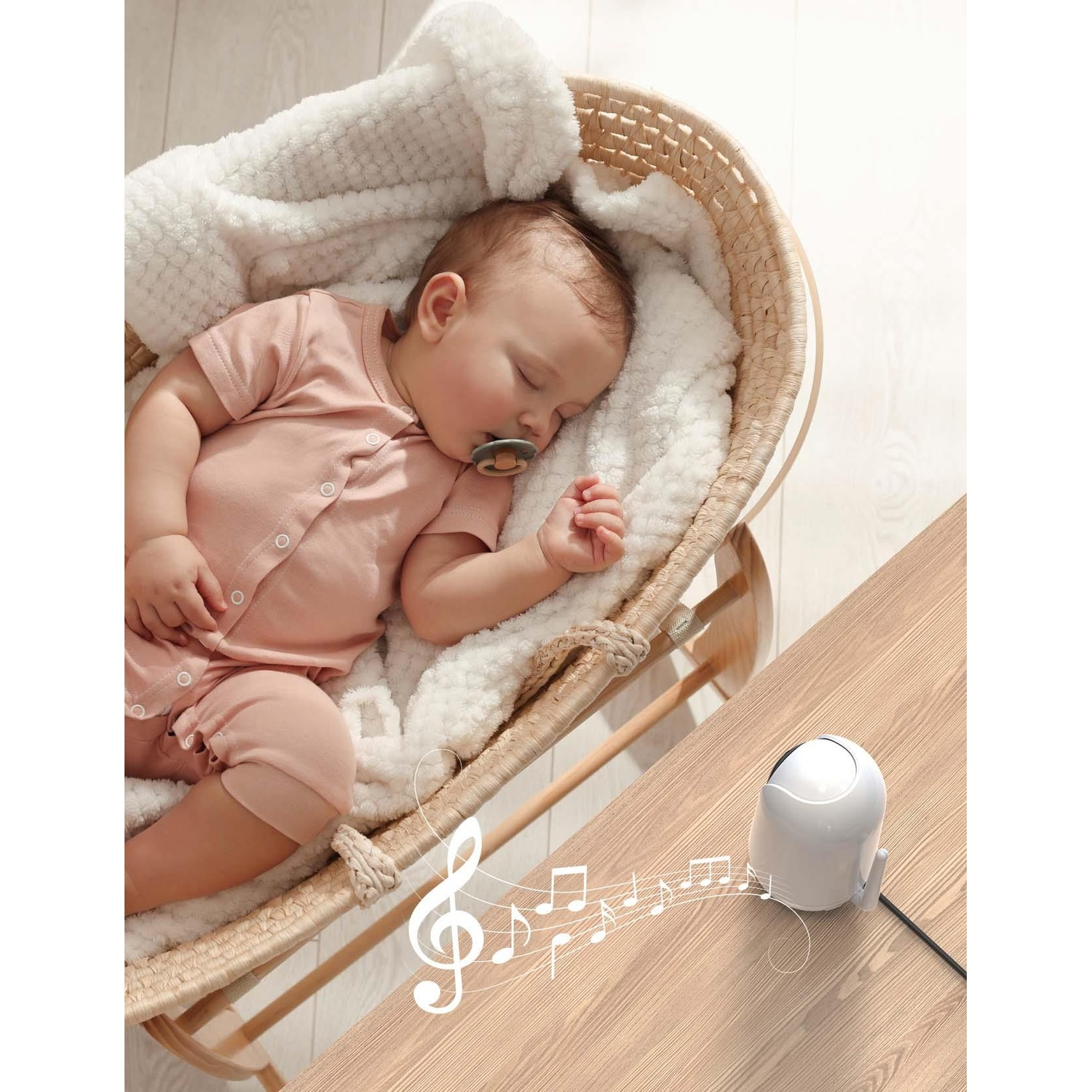 Bambino che dorme in una culla di vimini. Note musicali sono mostrate accanto a una macchina del suono bianca.
