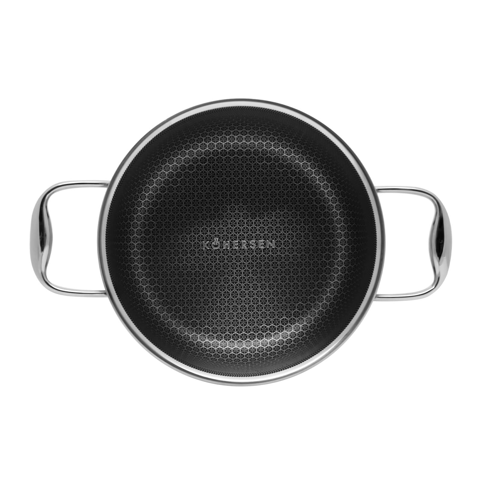 Widok z góry na czarny garnek z uchwytami. Wzór plastra miodu w środku. Białe tło.