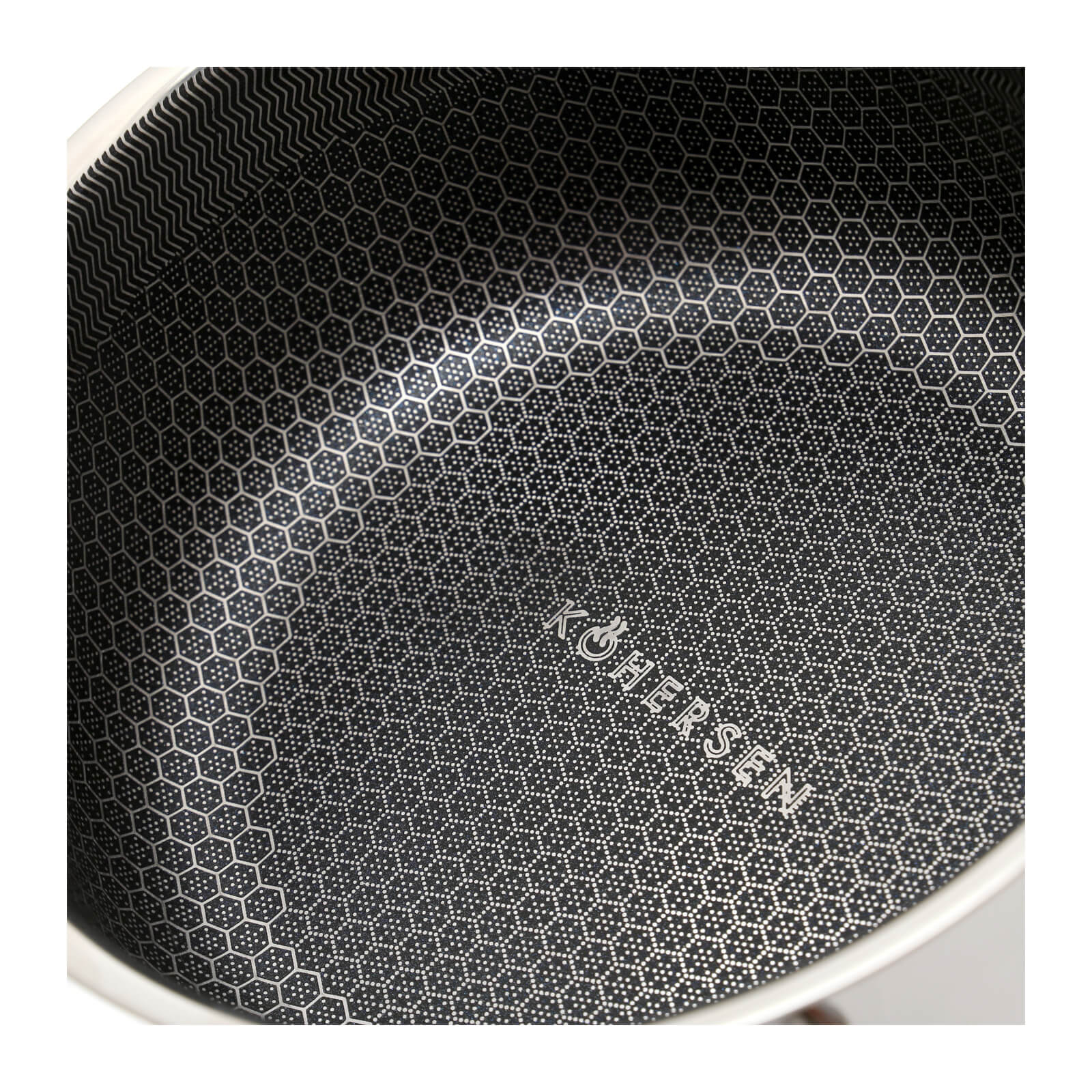 Zbliżenie na czarne i białe wnętrze patelni z wzorem plastra miodu i logo 'KÖHERSEN'.