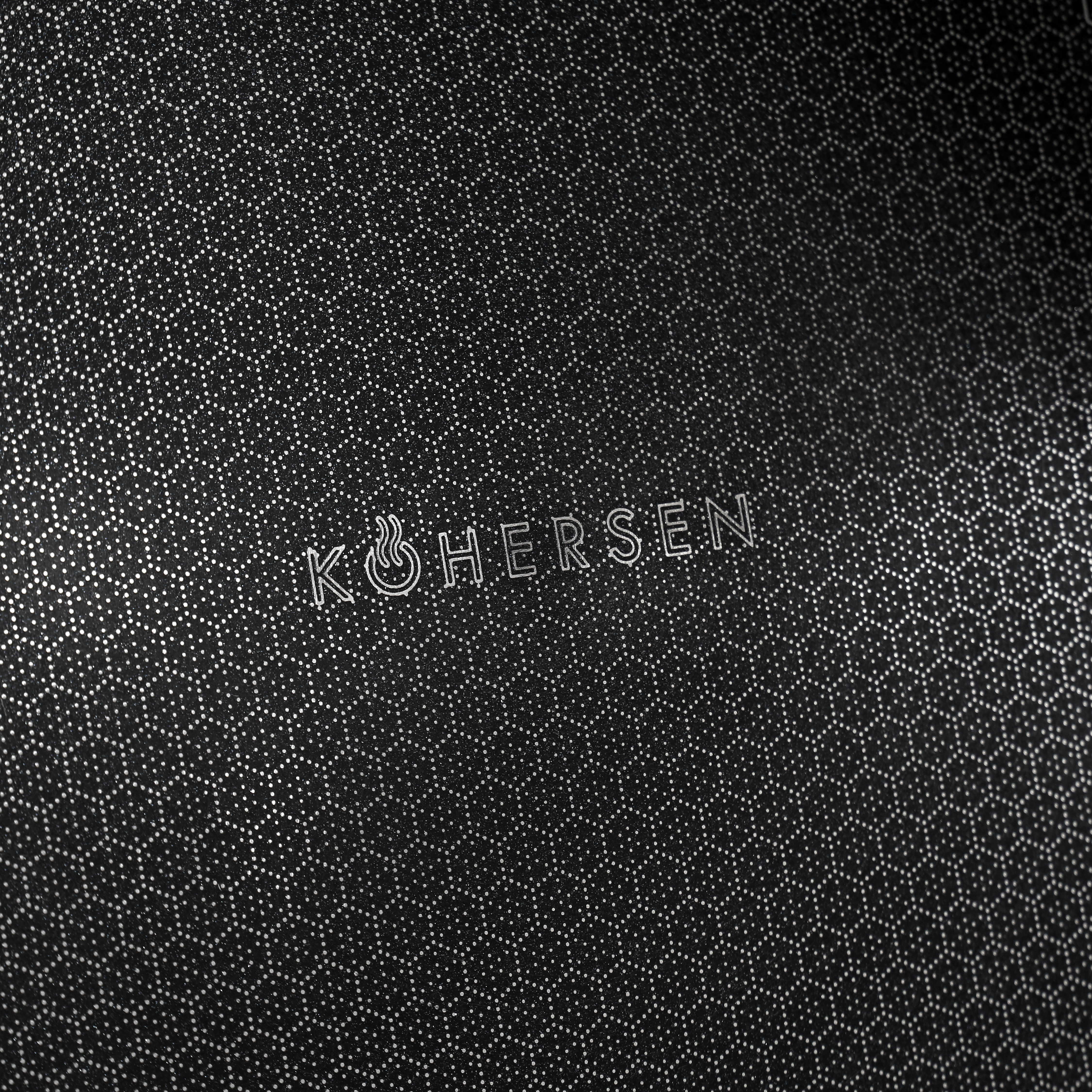 Zbliżenie czarnej powierzchni o wzorze plastra miodu i nazwie marki 'KOHERSEN'.