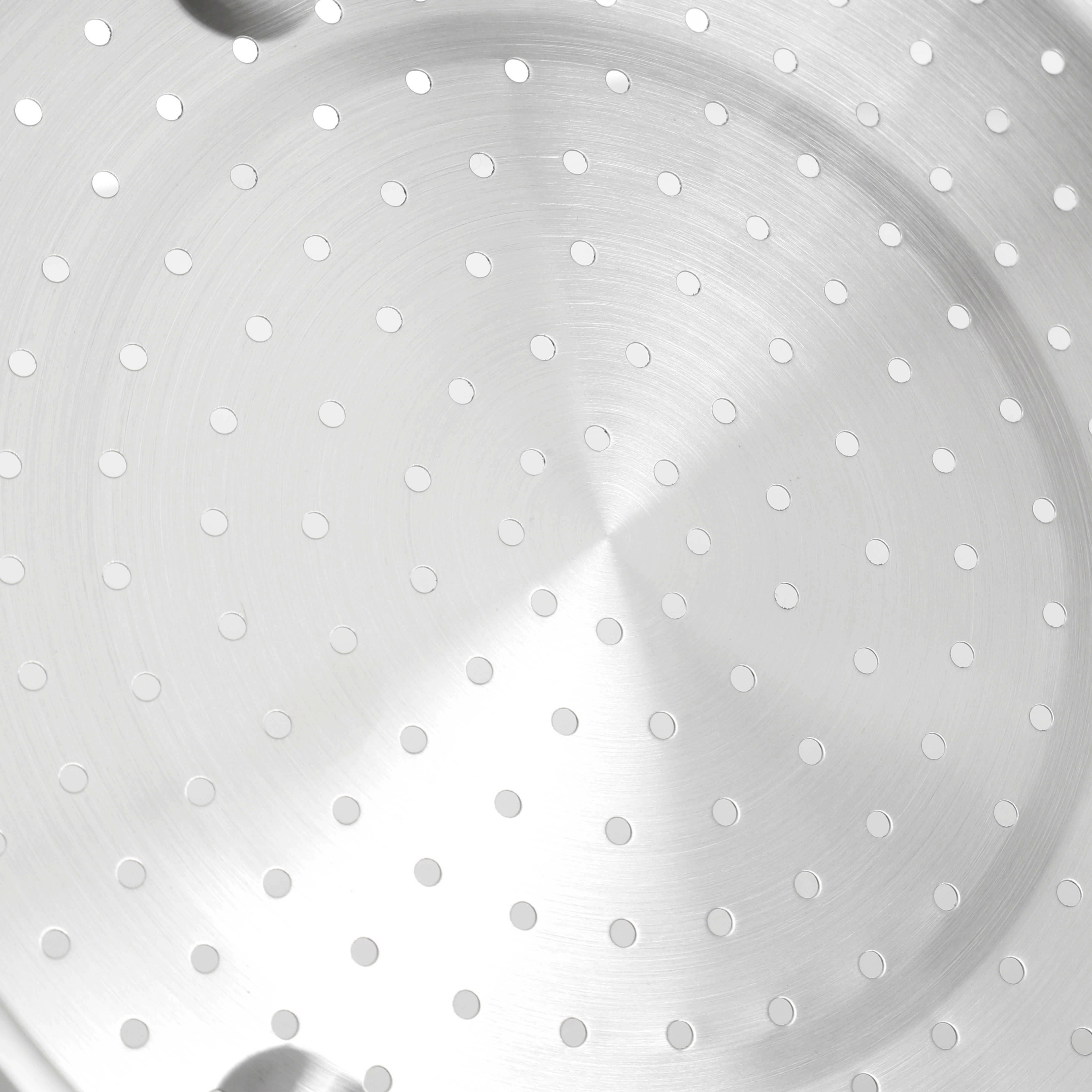 Zbliżenie dna garnka ze stali nierdzewnej, pokazujące koncentryczne okręgi i wiele małych otworów.