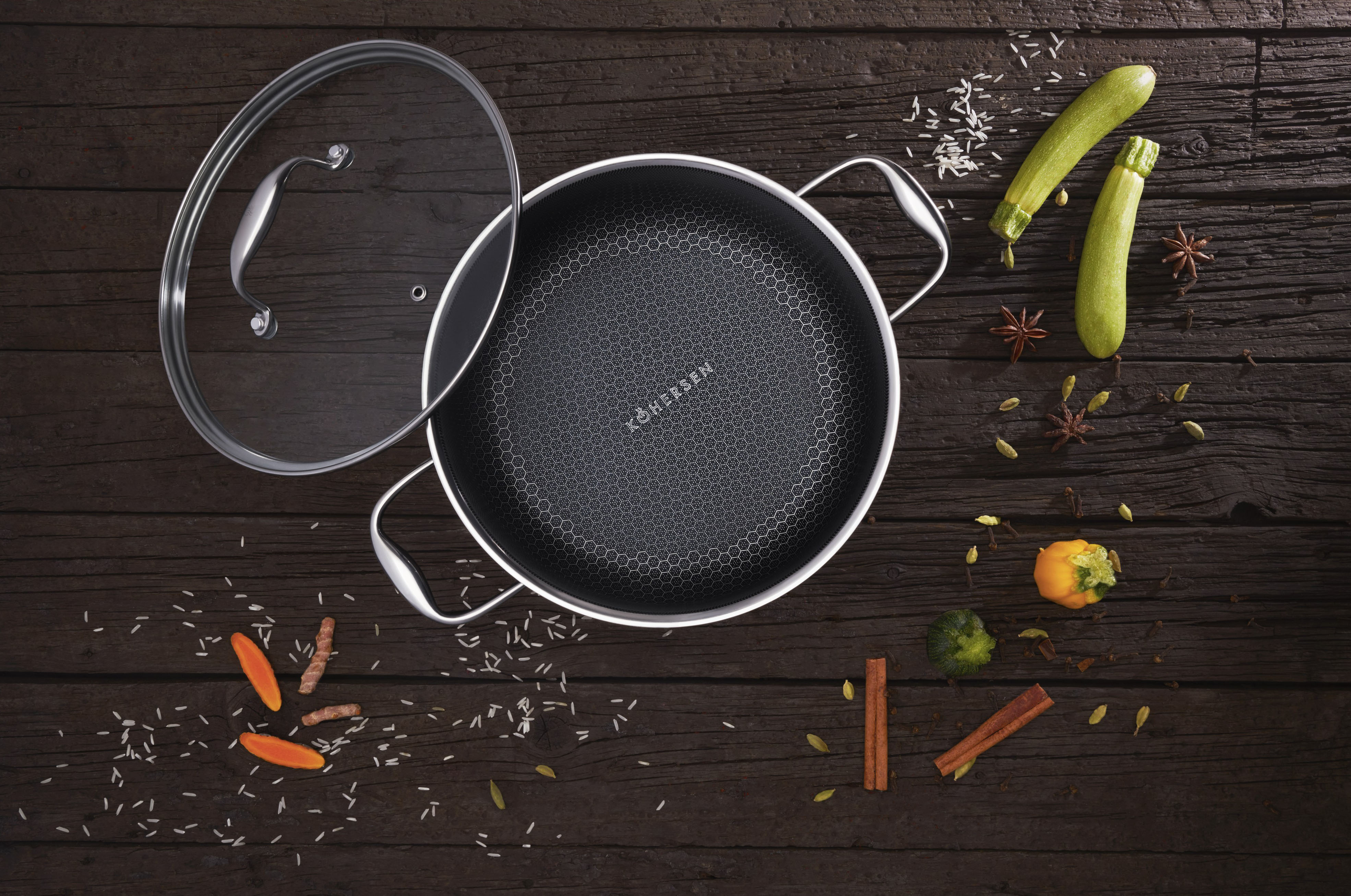 Widok z góry na patelnię z warzywami i przyprawami. Patelnia jest ciemna, o wzorze plastra miodu.