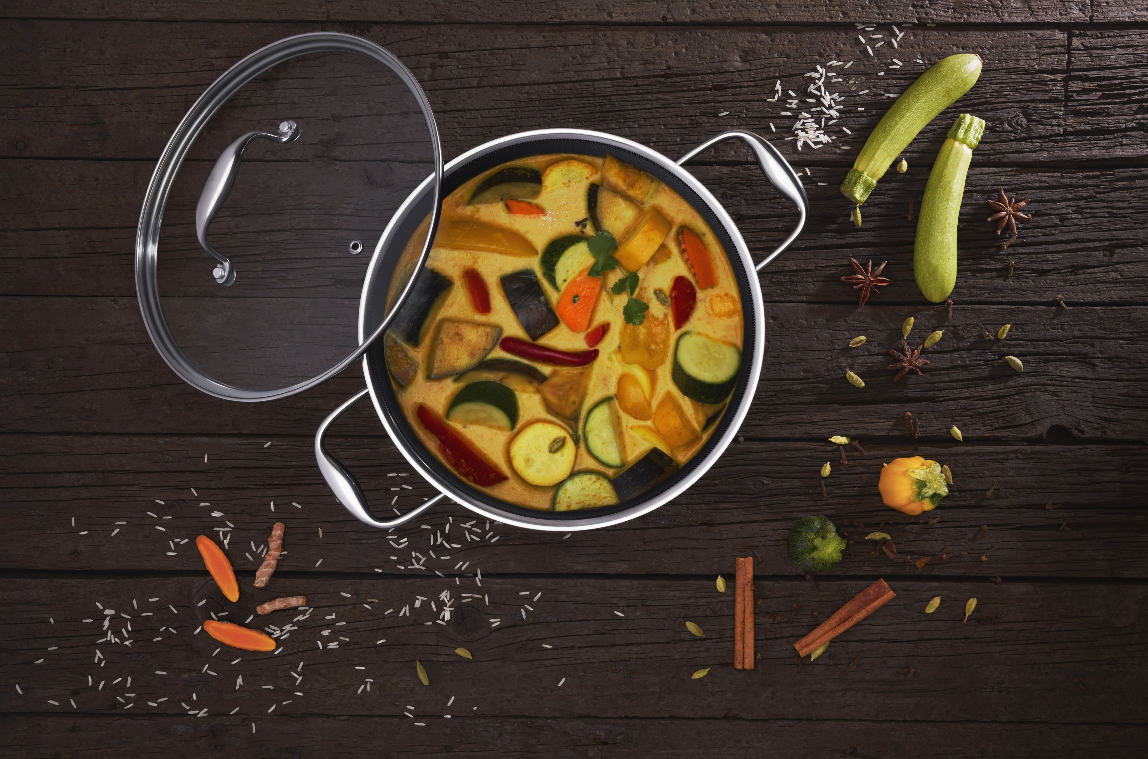 Widok z góry na garnek z warzywami. Jest szklana pokrywka.