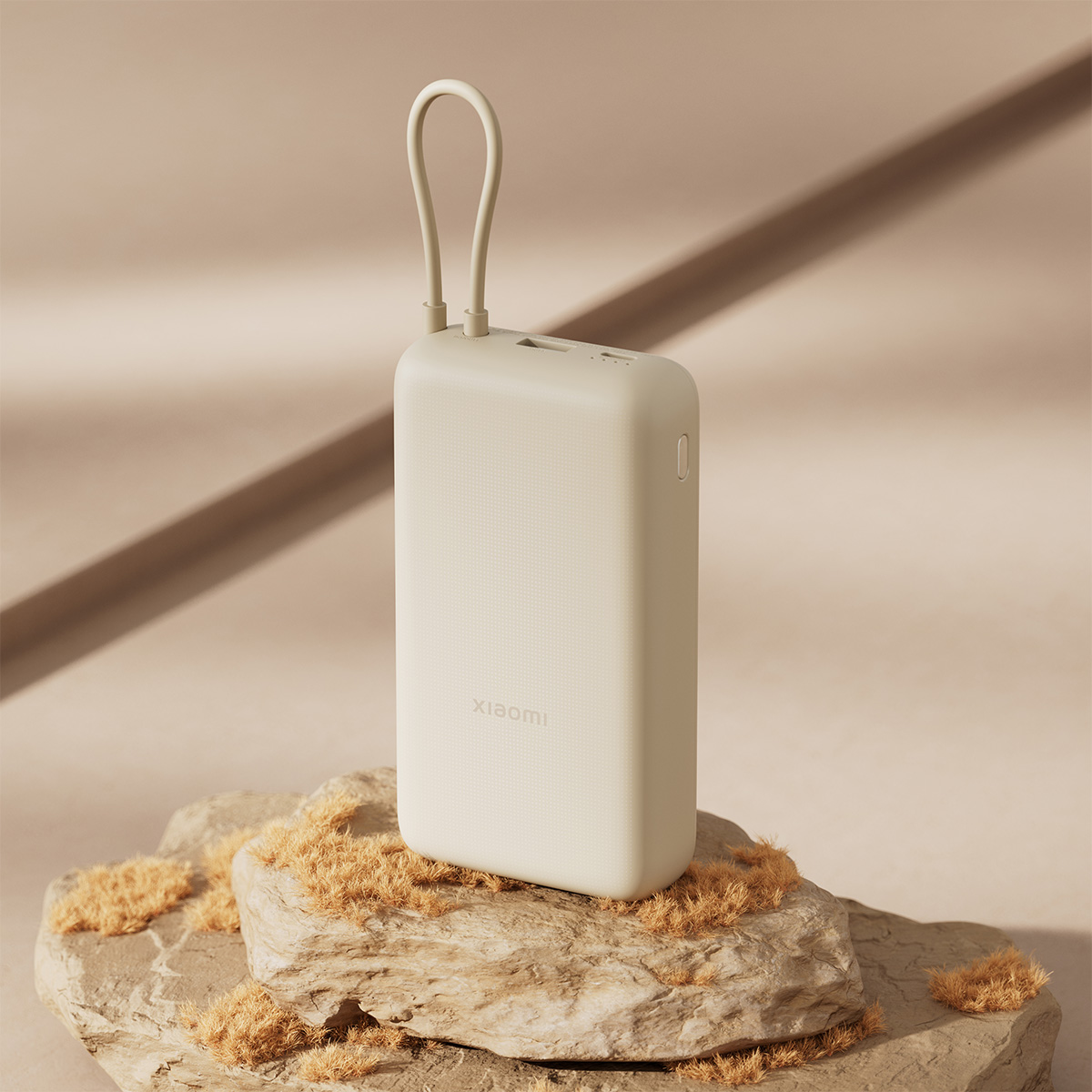 Bézs power bank egy kövön, hurokkal, Xiaomi logóval.