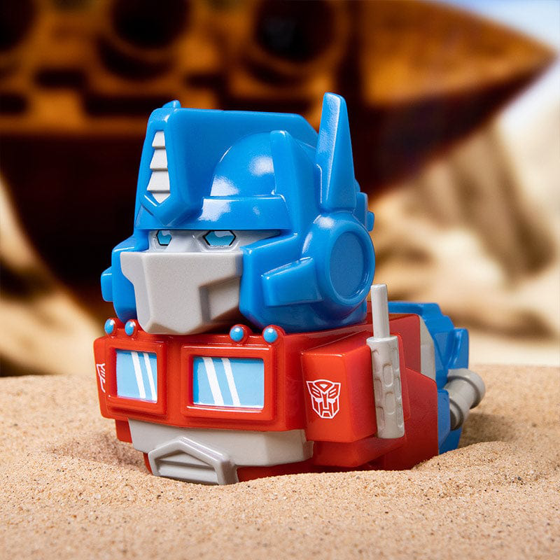 Kék és piros színű játékrobot. Egy Transformer játék homokon.