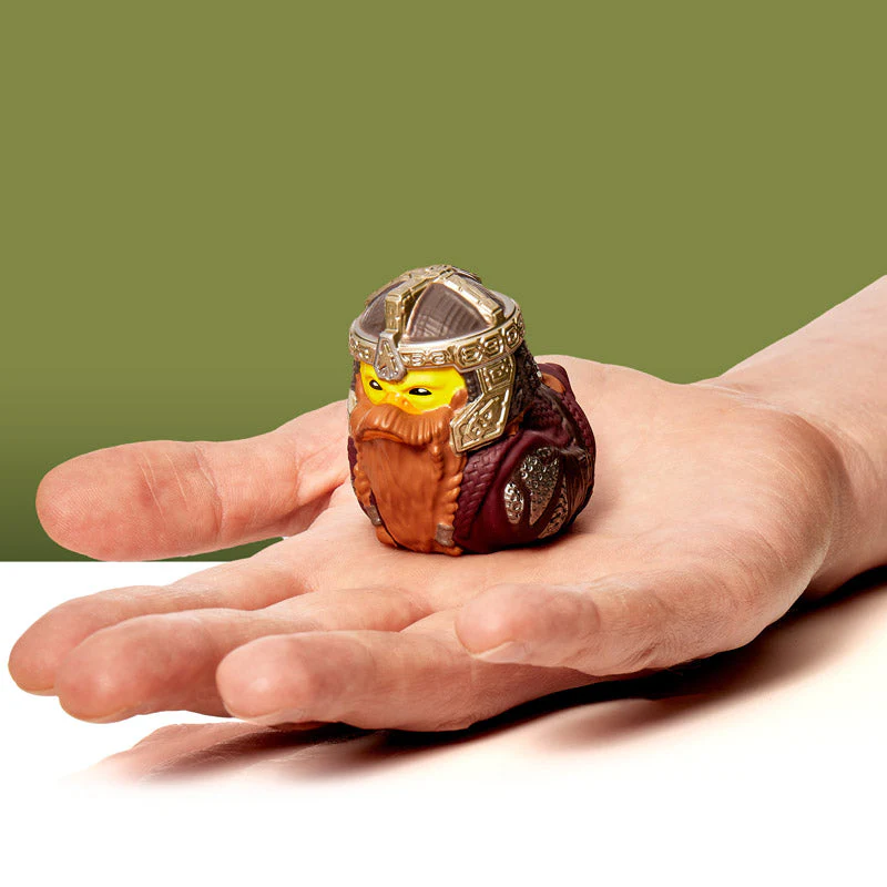 Egy kéz egy kis játék viking figurát tart. A figura barna, sárga és sisakja van.