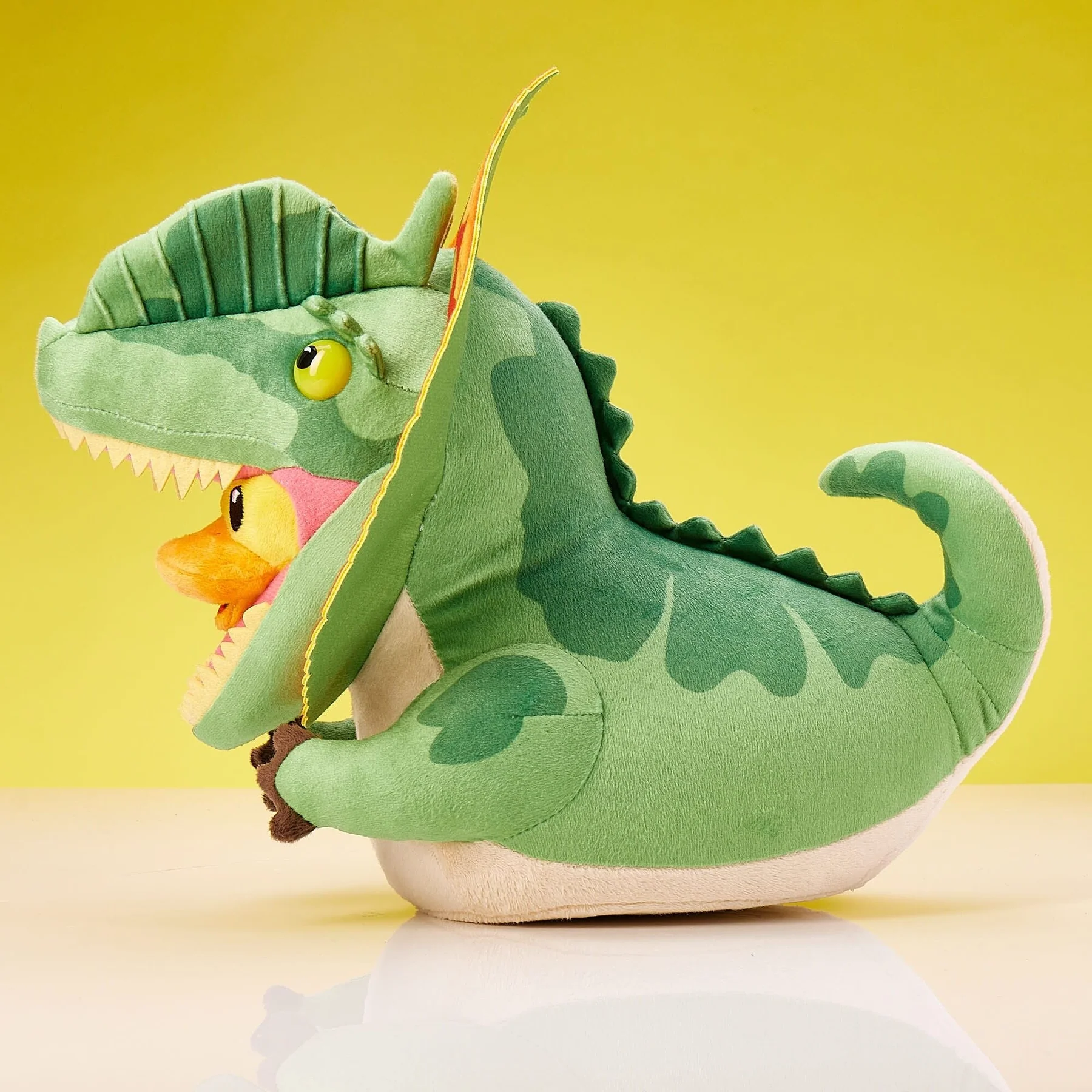 Zöld dinoszaurusz plüssjáték egy kacsás plüssjátékkal benne.