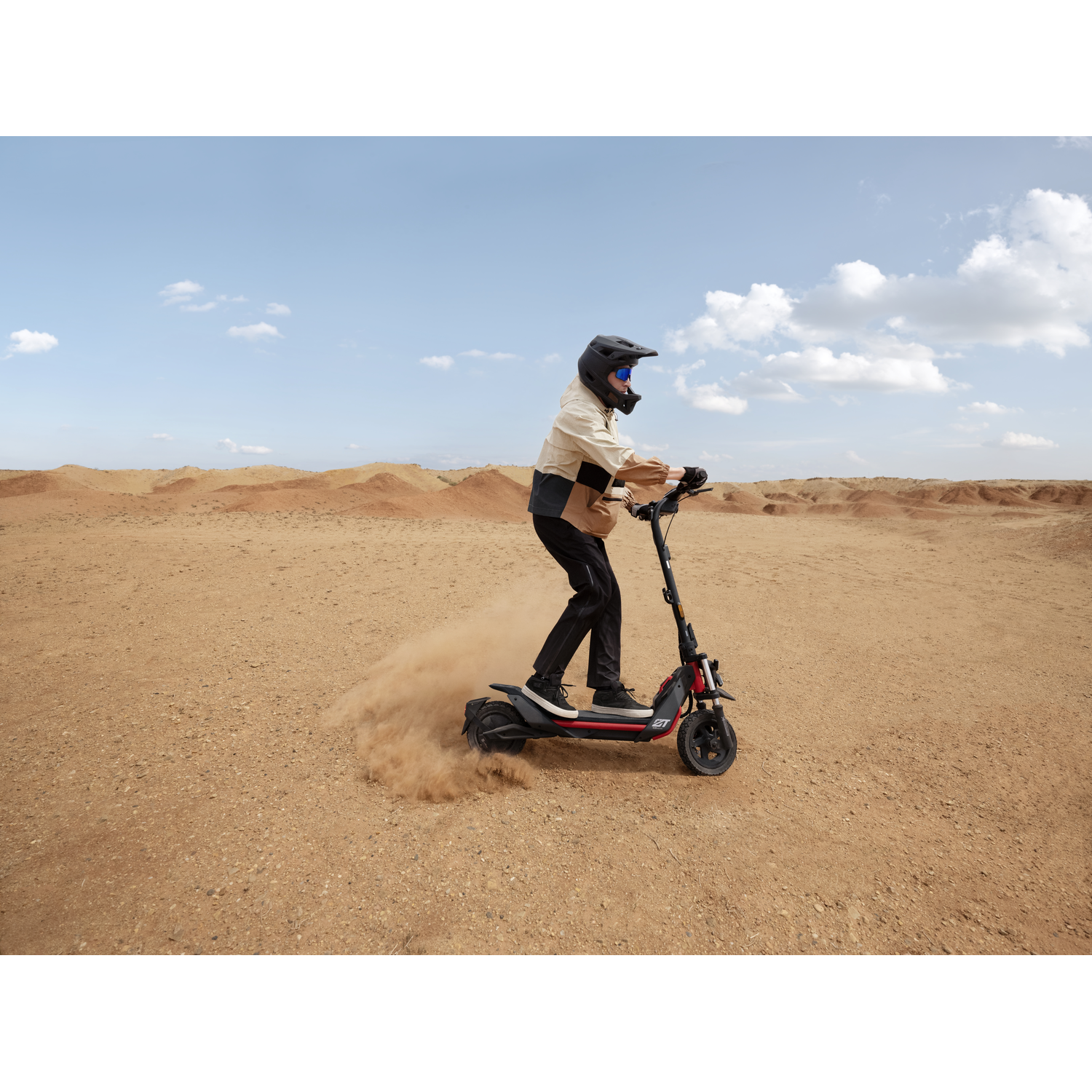 Persoon die op een scooter in de woestijn rijdt.