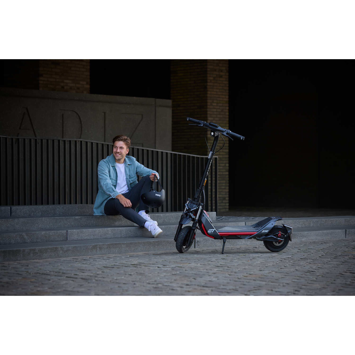 Man zit op trappen naast een elektrische scooter.