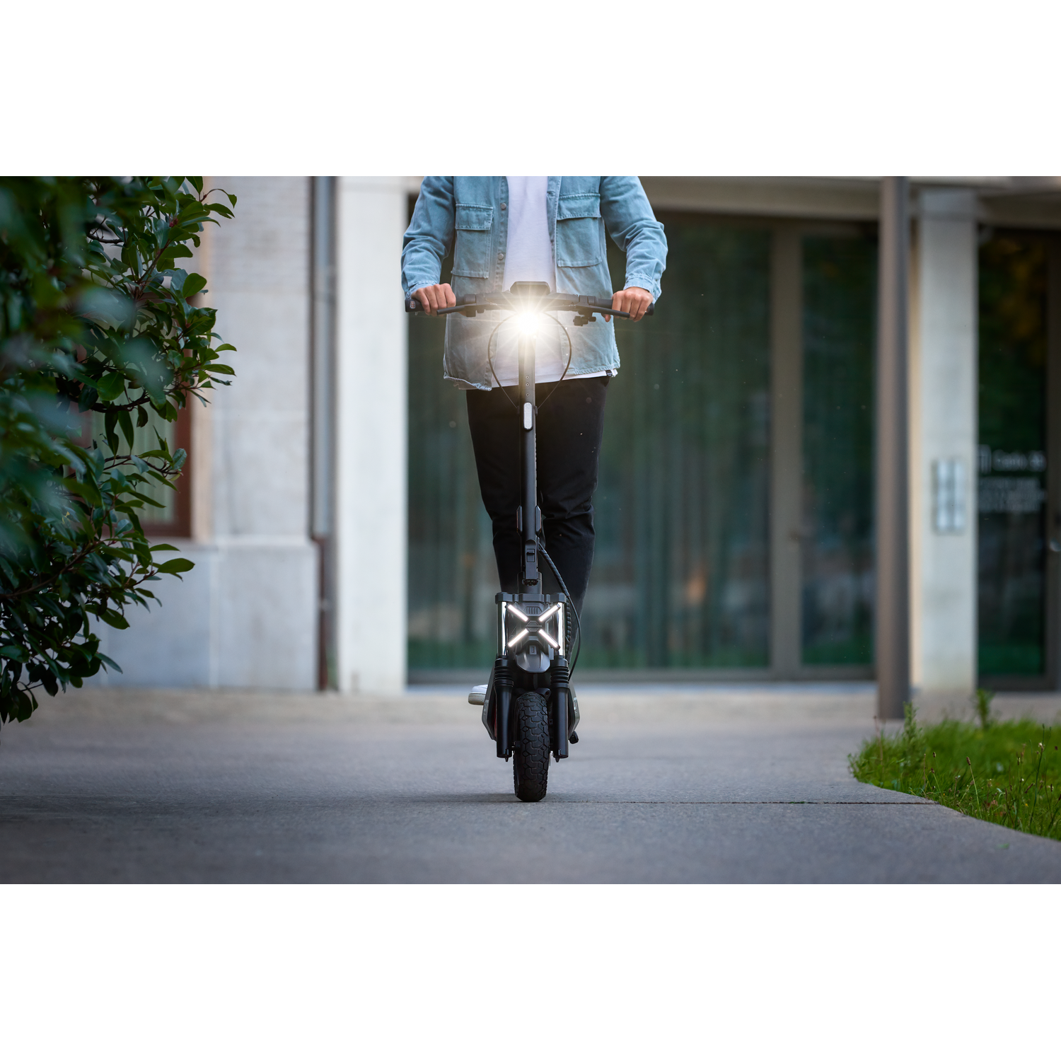 Persoon op een elektrische scooter op een verhard pad. De scooter heeft een felle koplamp.