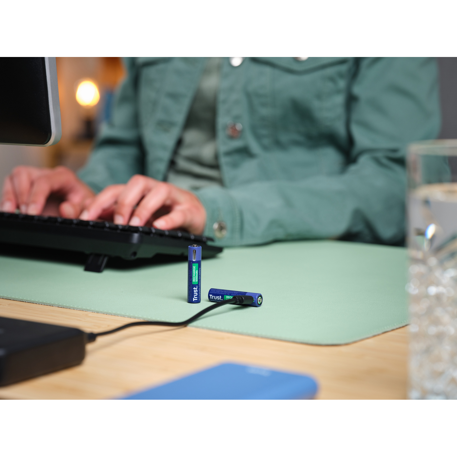Deux piles bleues Trust. et un clavier sur un bureau vert.
