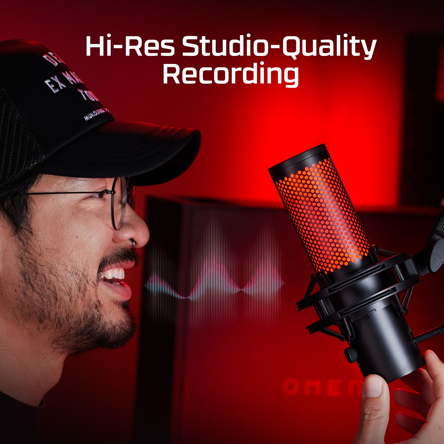 Homme parlant dans un microphone noir et orange, fond rouge, graphique d'onde audio.