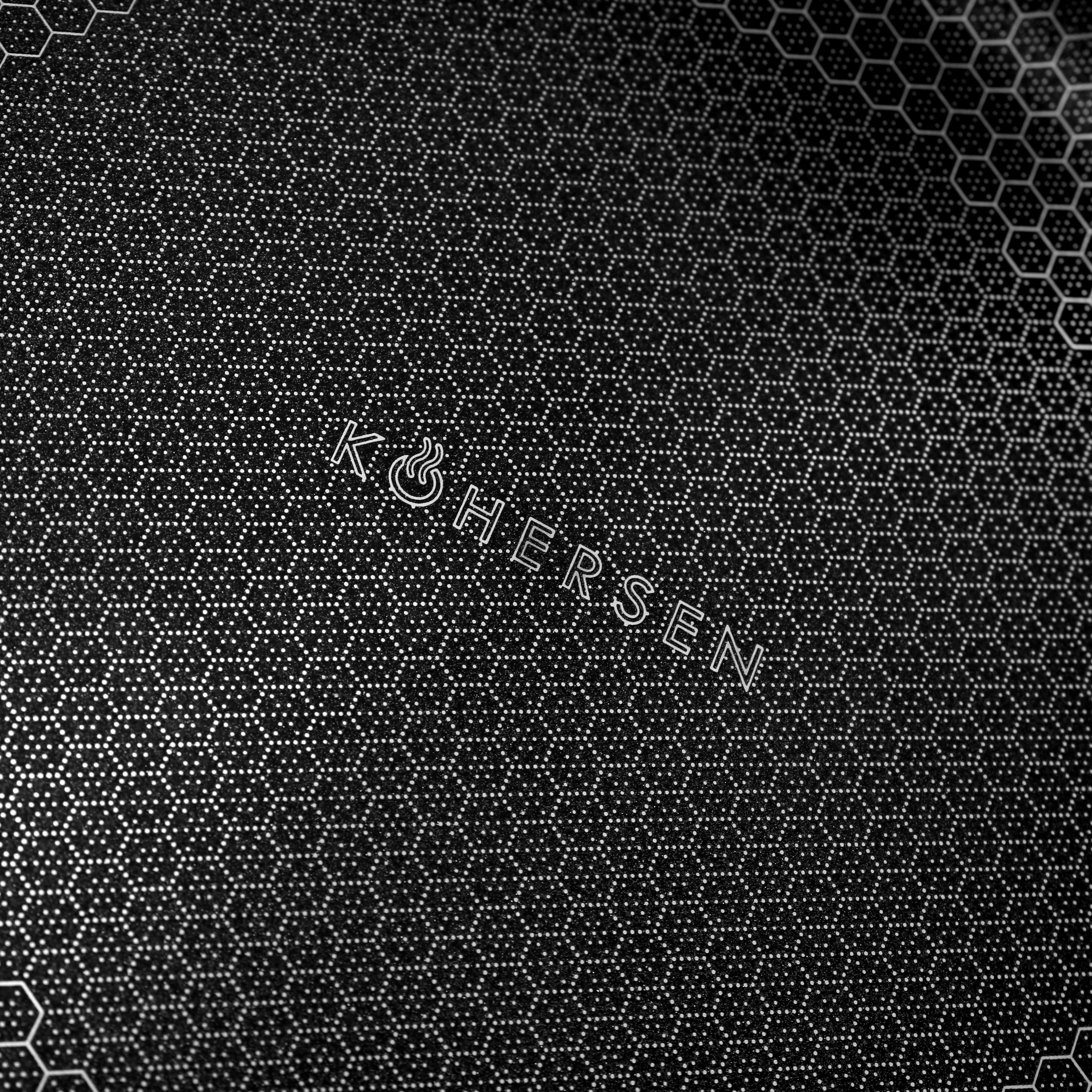 Zbliżenie czarnej patelni z teksturowaną powierzchnią plastra miodu i tekstem.