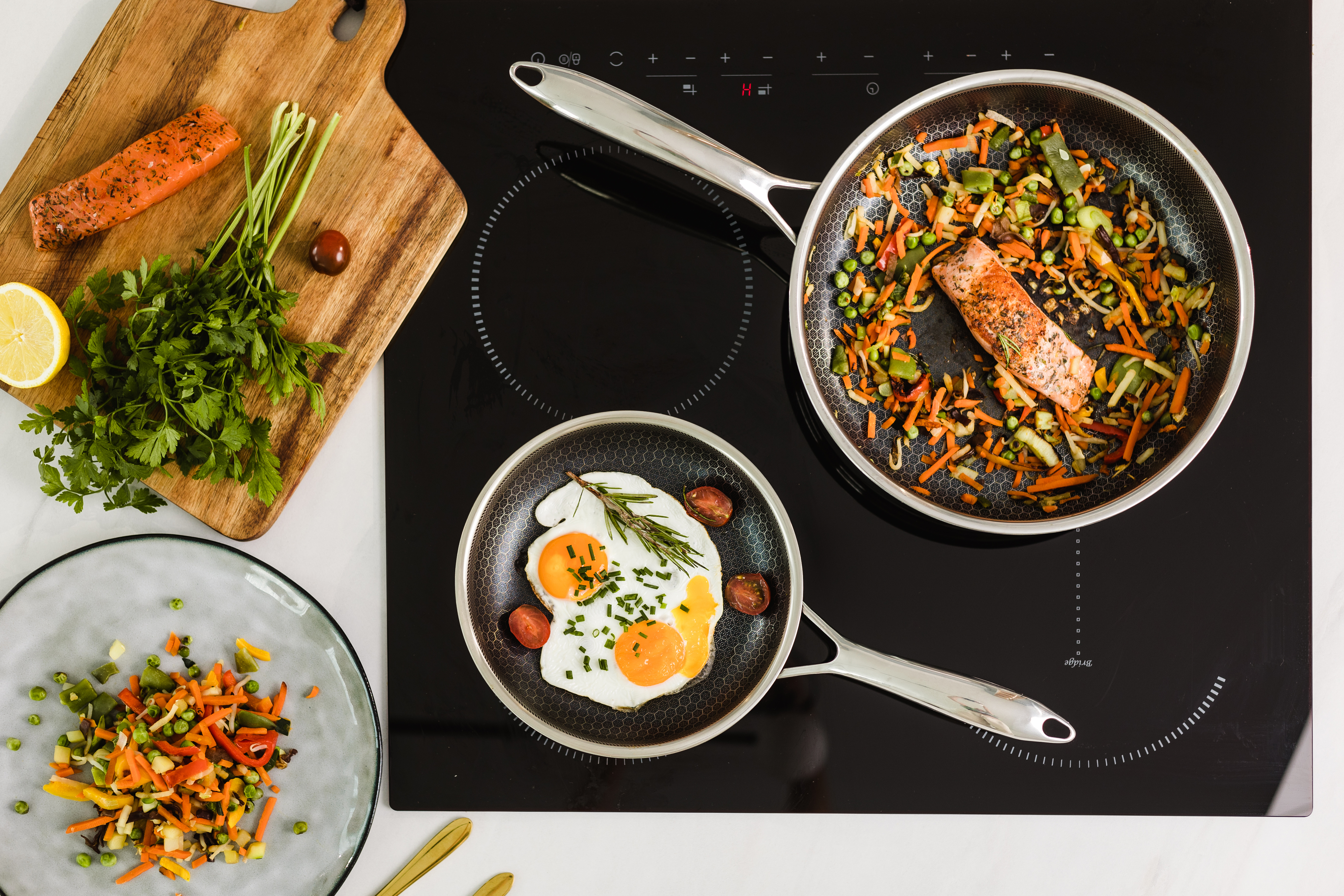 Widok z góry na patelnię z jedzeniem i deskę do krojenia z warzywami na kuchence.