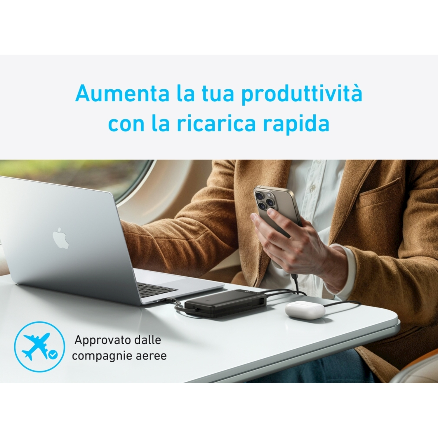 Una persona su un aereo utilizza un laptop e carica un telefono con un caricabatterie portatile.