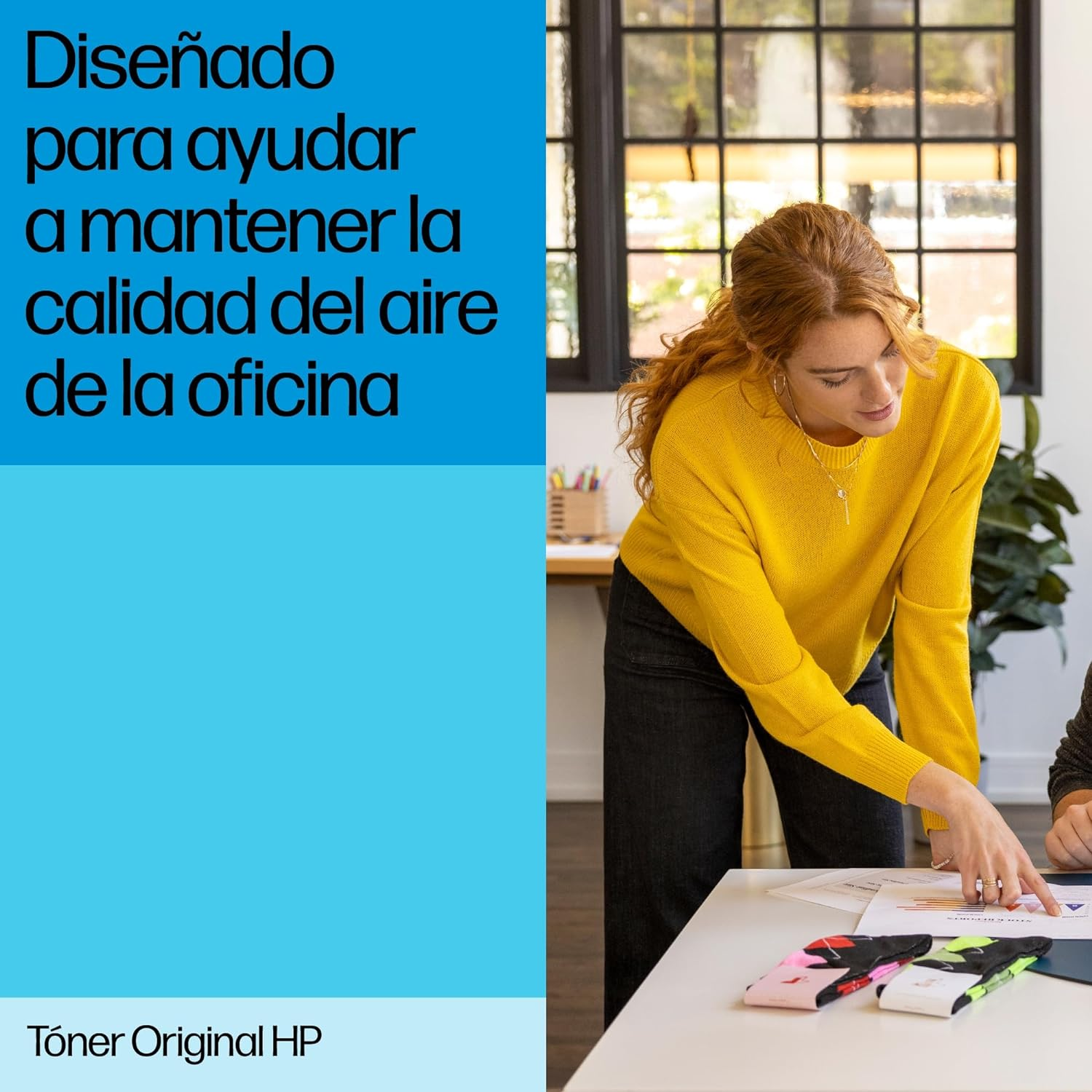Mujer con suéter amarillo señalando papeles en mesa blanca. Fondo azul.