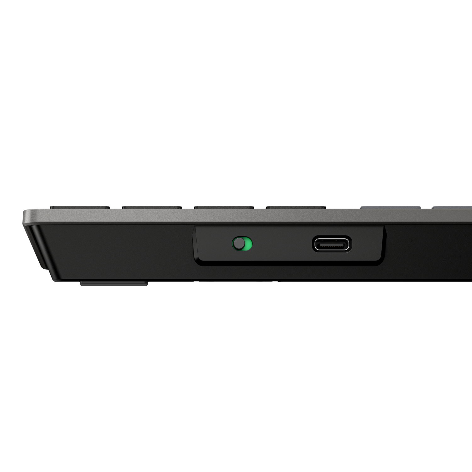Close-up van een zwarte toetsenbordzijkant, met een groen licht en een USB-C poort op een zwart oppervlak.