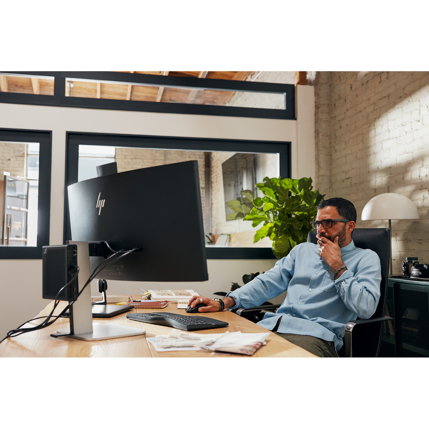 Man sitting at a desk with a computer, looking at the monitor.