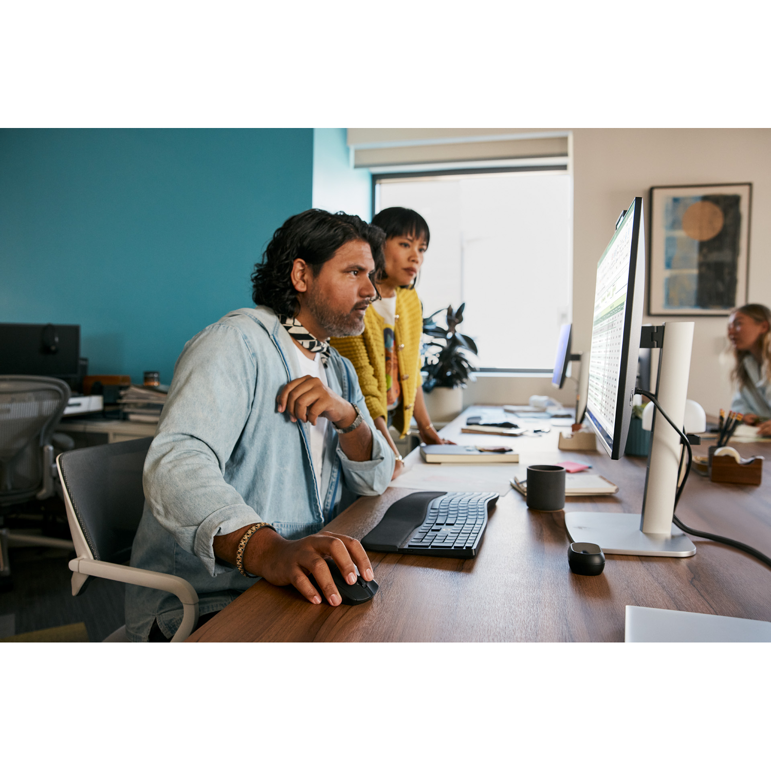 Two people are looking at a computer screen in an office setting.