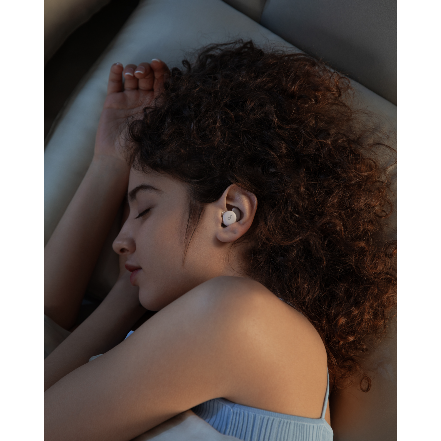A woman sleeps with an earbud in one ear.