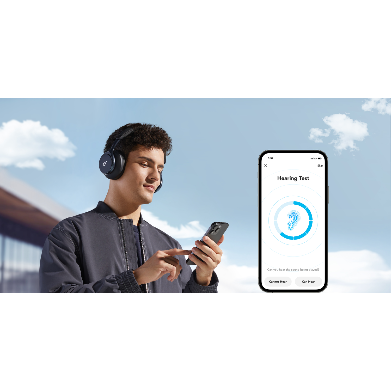 A man with headphones is using a phone with a hearing test app. The sky is blue with clouds.