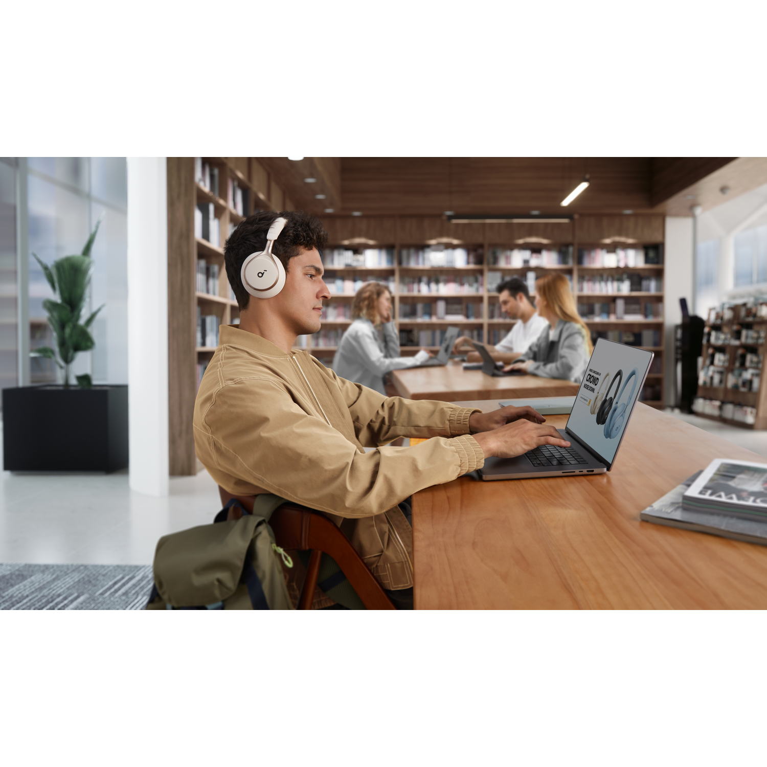 Homme avec casque travaillant sur un ordinateur portable dans une bibliothèque.