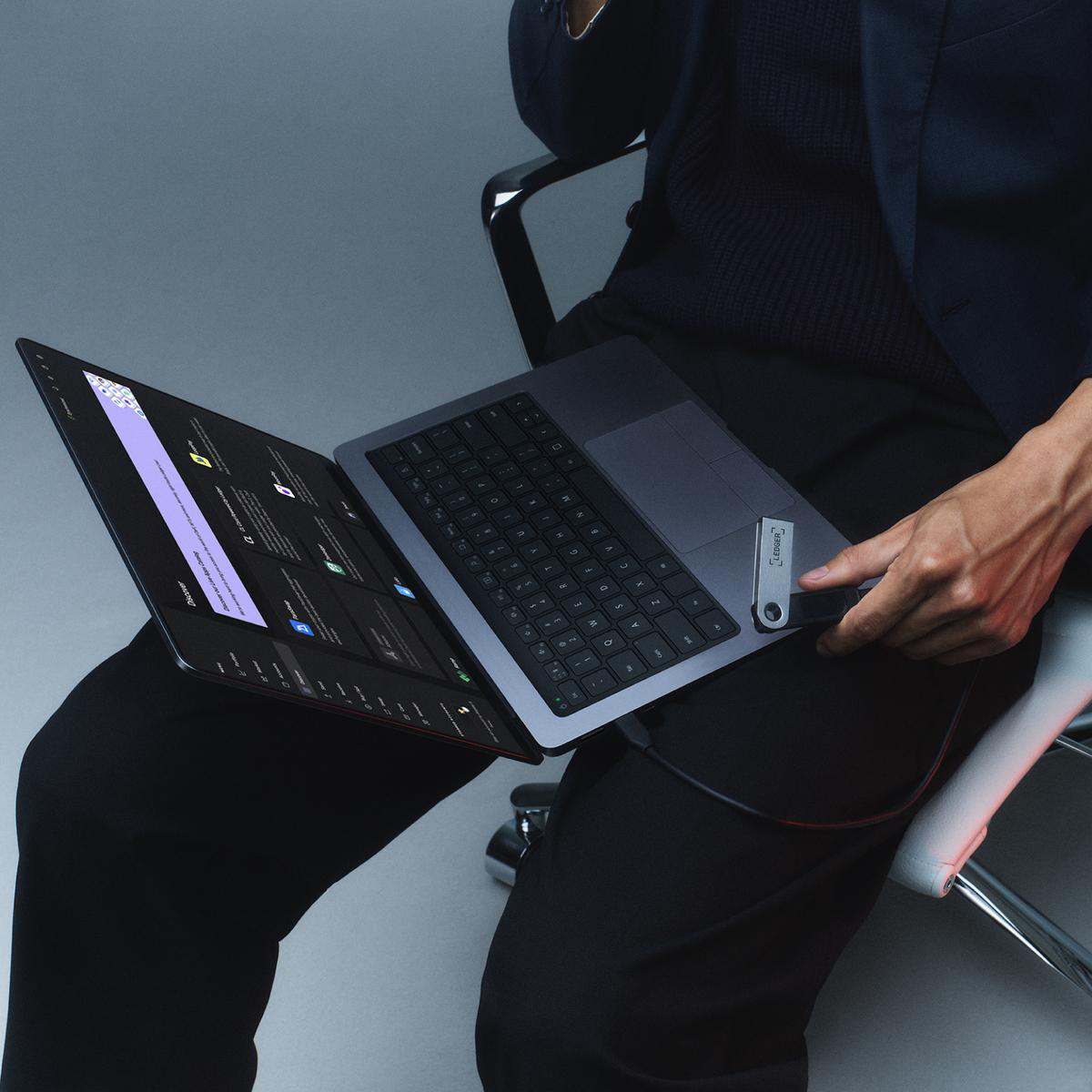 Eine Person sitzt und hält einen geöffneten Laptop. Der Laptop ist angewinkelt und zeigt eine Website.