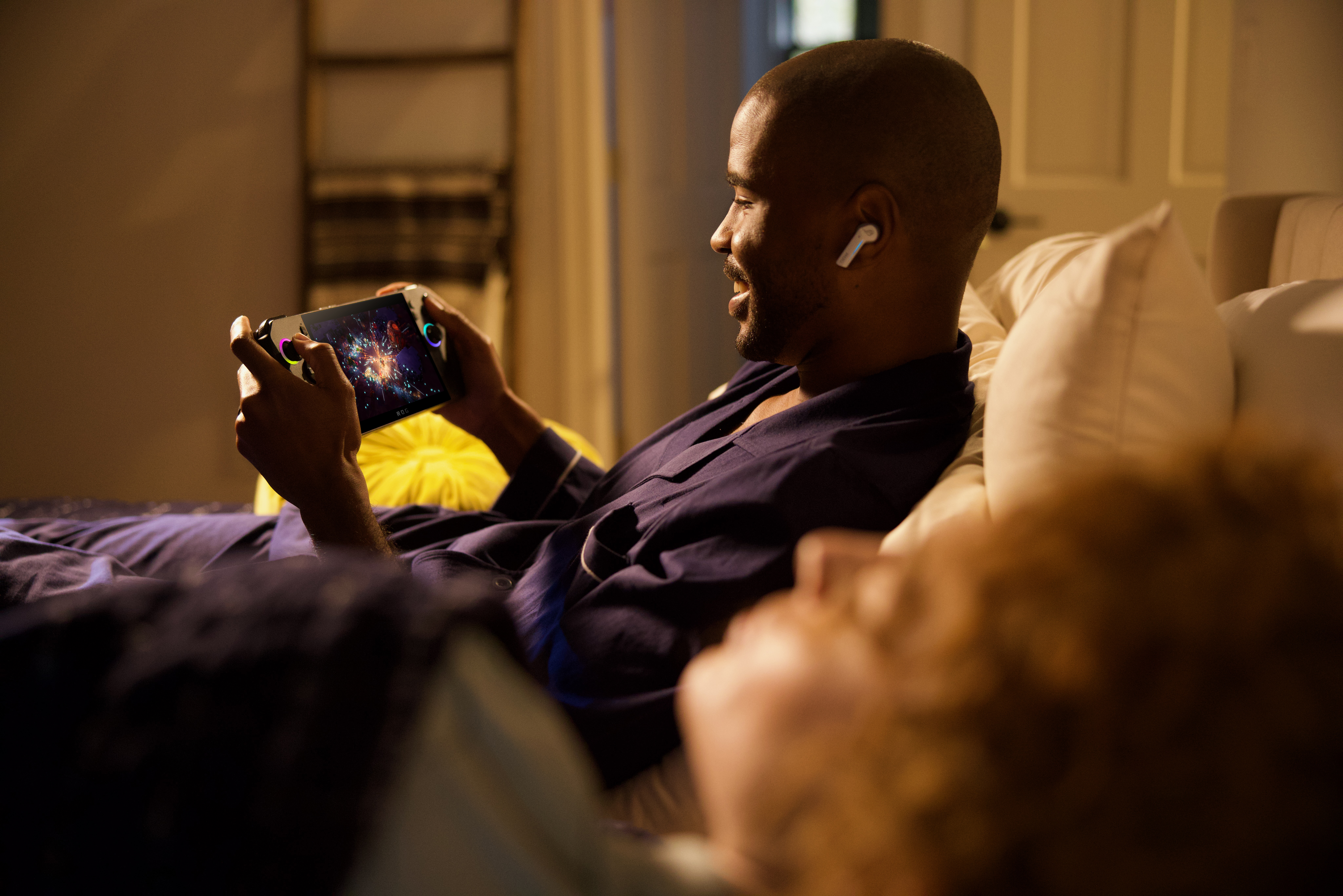 Ein Mann spielt ein Handheld-Spiel im Liegen.