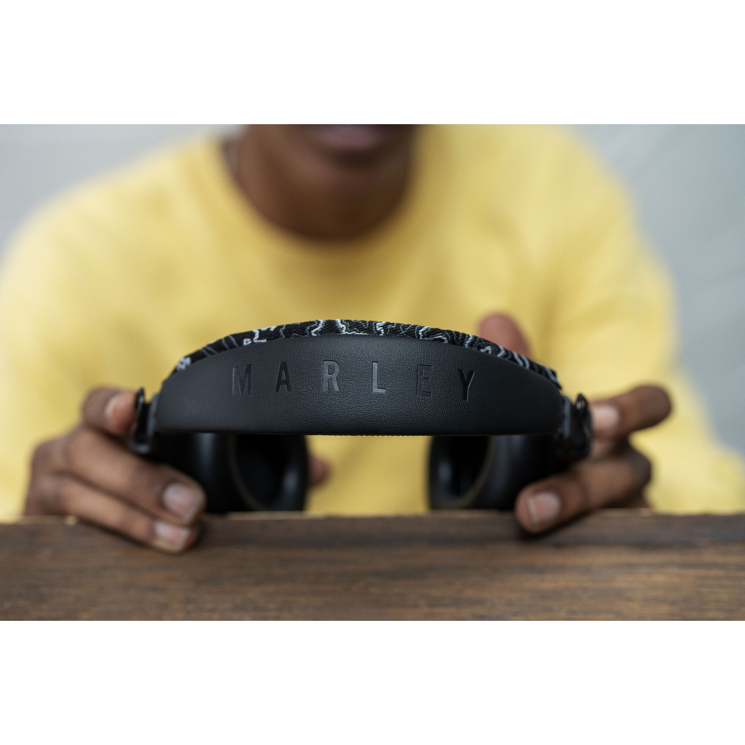 Une personne tient un casque Marley noir, le nom de la marque est visible.