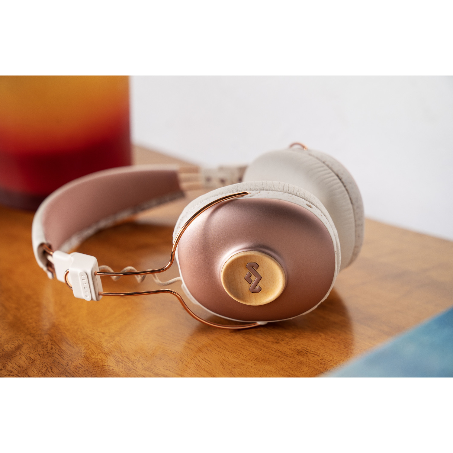 Casque audio sur une surface en bois. Écouteurs roses avec des accents dorés. Blanc et marron.