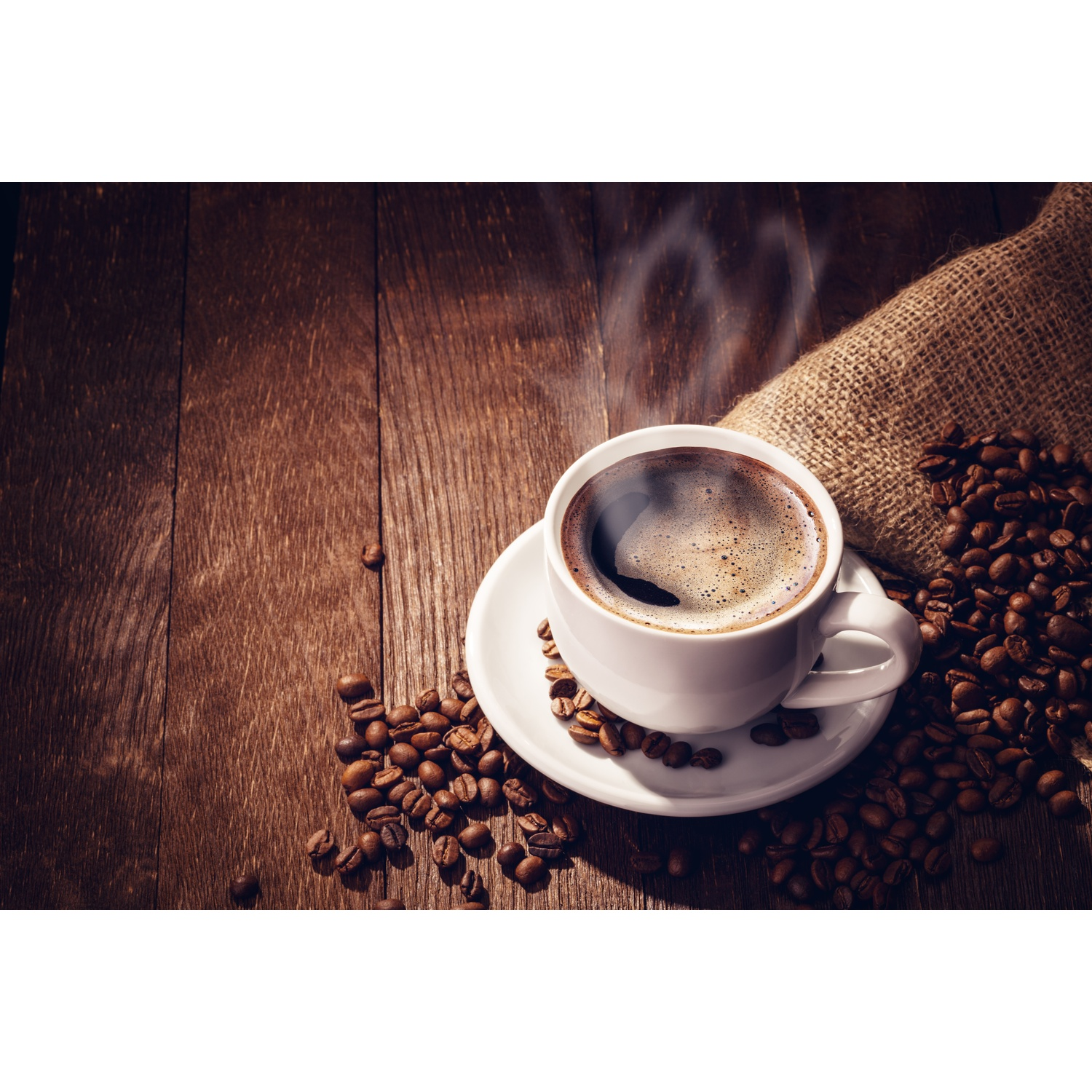 Caffè in una tazza bianca su un piattino. Chicchi di caffè e sacco di juta su una superficie di legno.