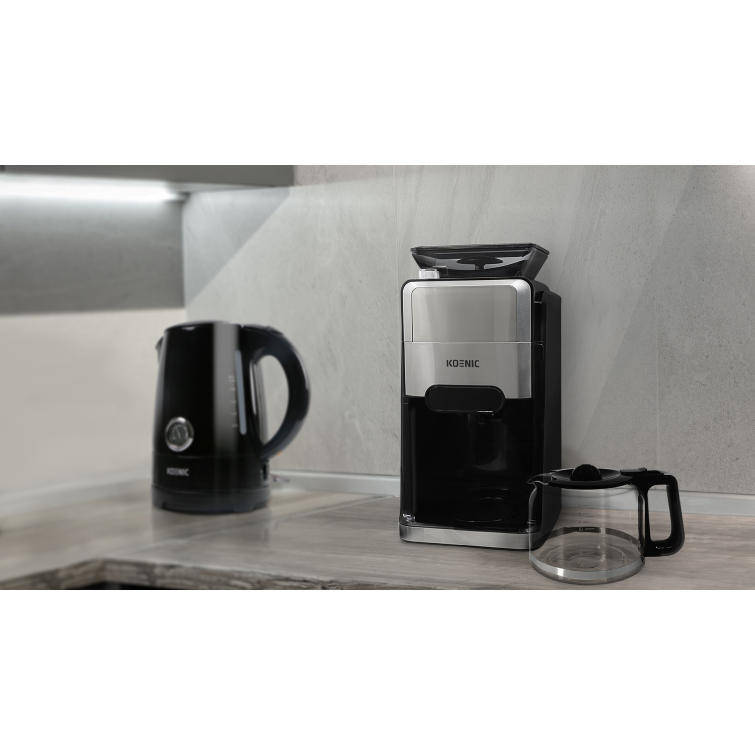 Piano cucina con un bollitore nero, una caffettiera e una caraffa di vetro.