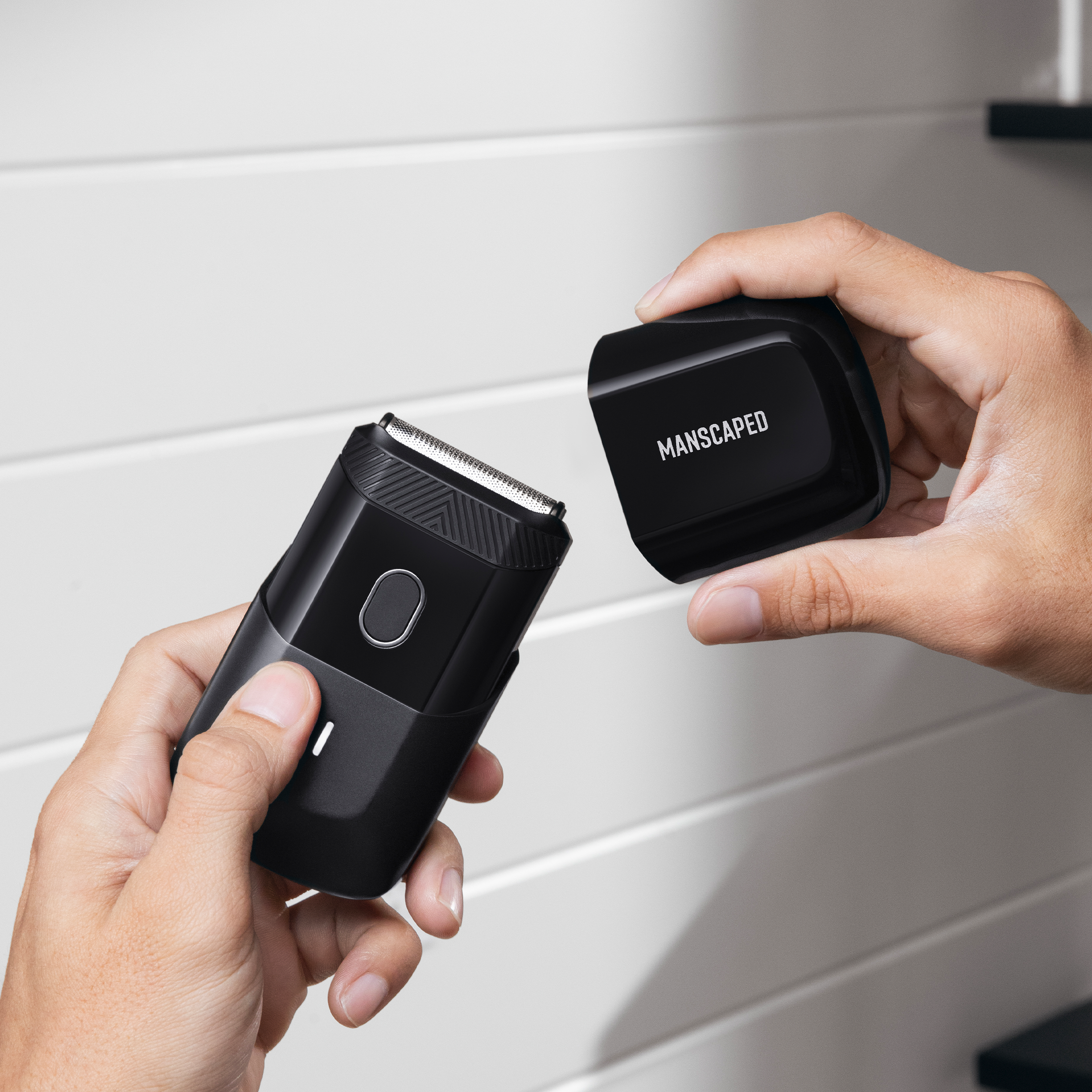 Des mains tiennent un rasoir électrique noir et son capuchon de chargement noir fermé.