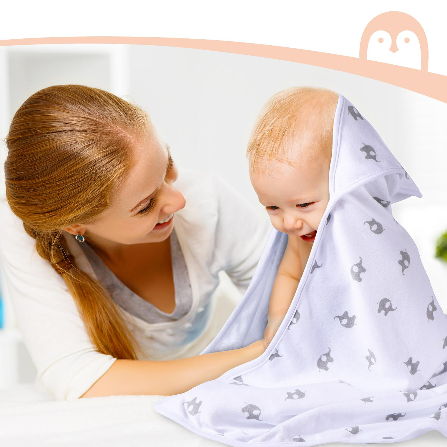 Eine Mutter und ein Baby im Badezimmer. Das Baby ist in ein weißes Handtuch mit grauem Elefantenmuster gewickelt.