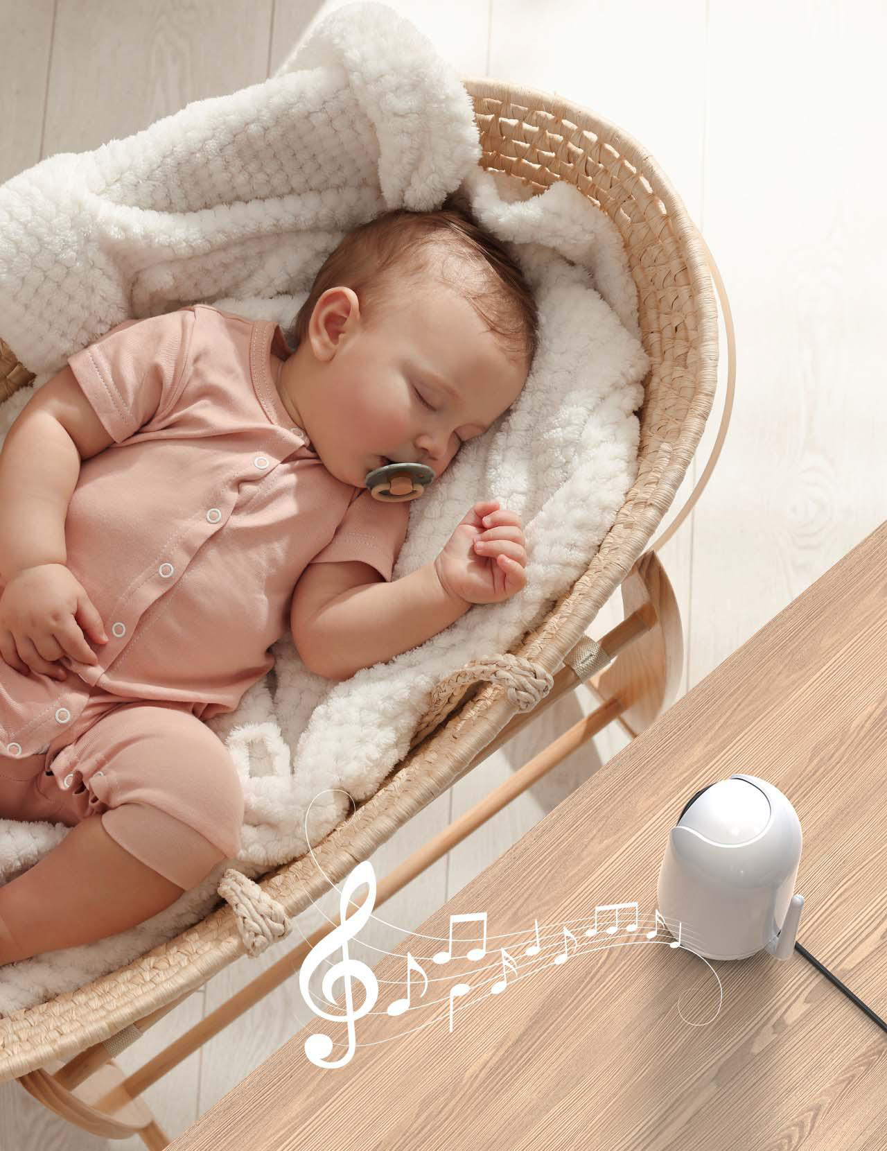 Ein Baby schläft friedlich in einer Weidenkorb-Wiege, mit einer Geräuschmaschine in der Nähe und Noten.
