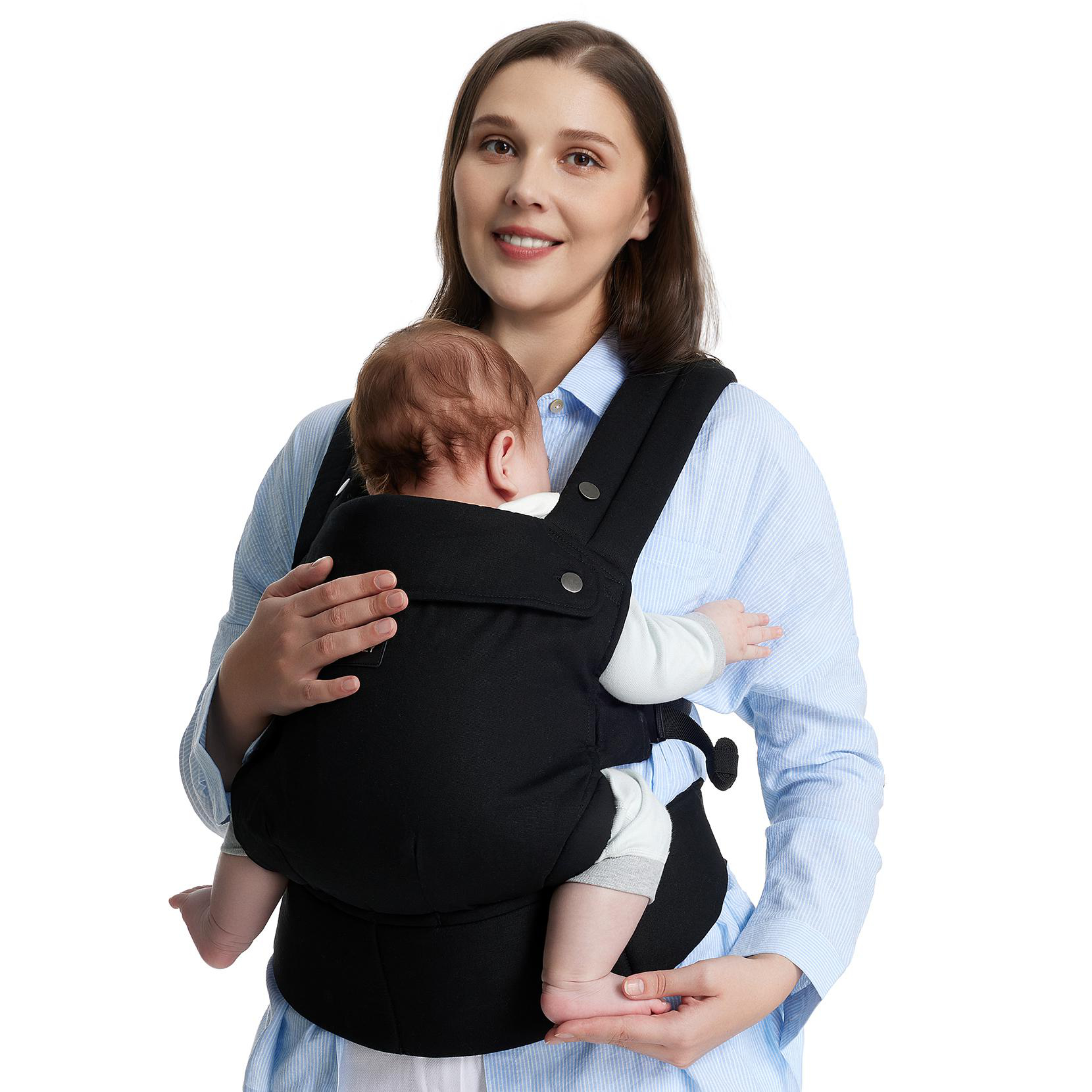Frau hält Baby in schwarzer Babytrage, lächelt in die Kamera.