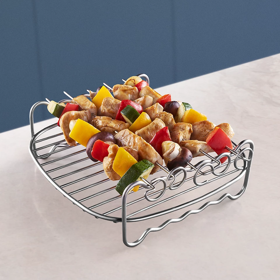 Grillezett kebabok egy fémrácson, színes hús- és zöldségszeletekkel.