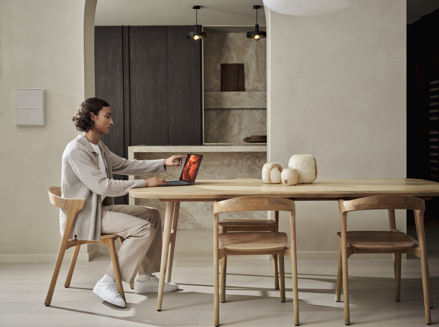 Persona trabajando en una laptop en una mesa de madera, sentada en una silla.