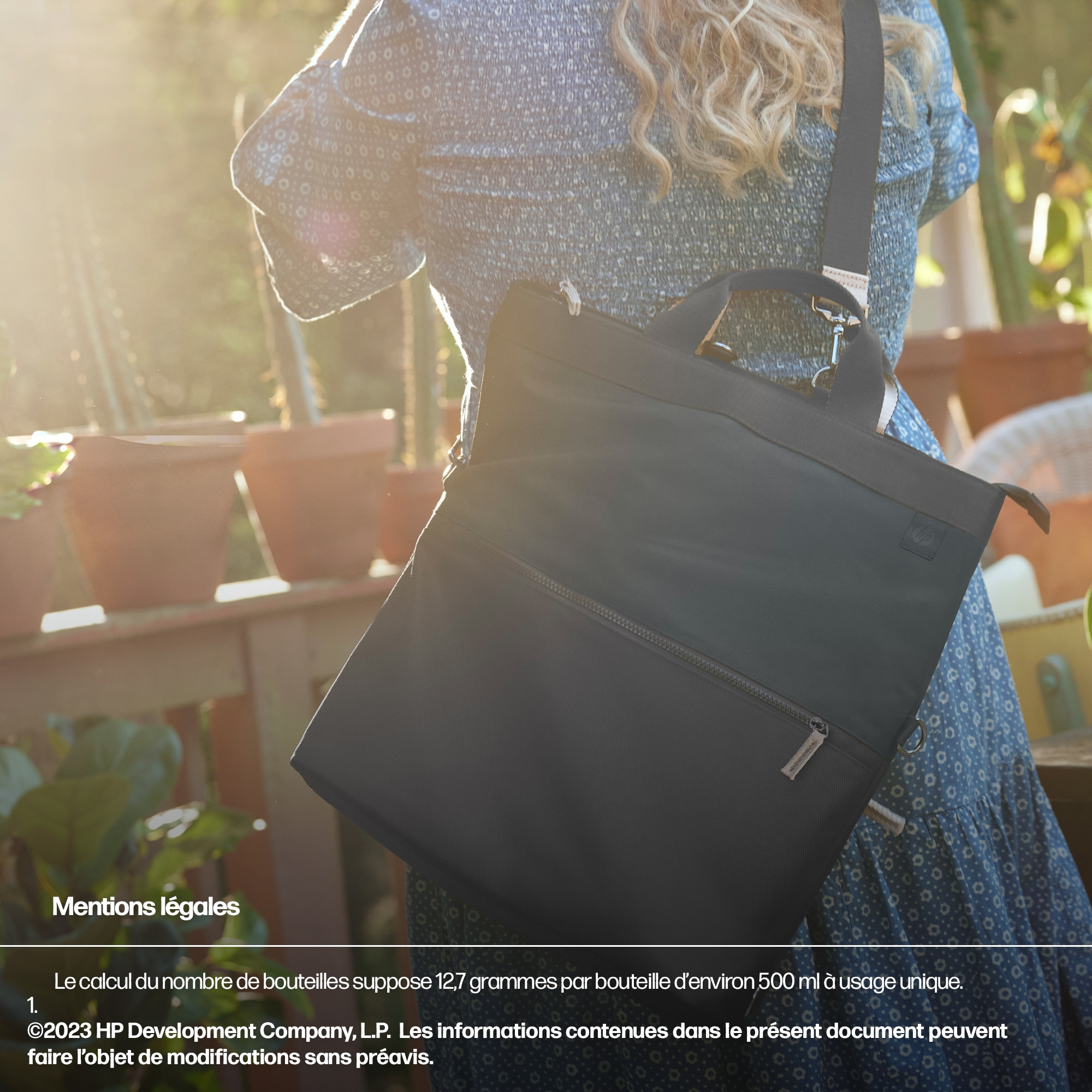Une femme portant un sac fourre-tout noir, debout dans un jardin avec des plantes en pot.