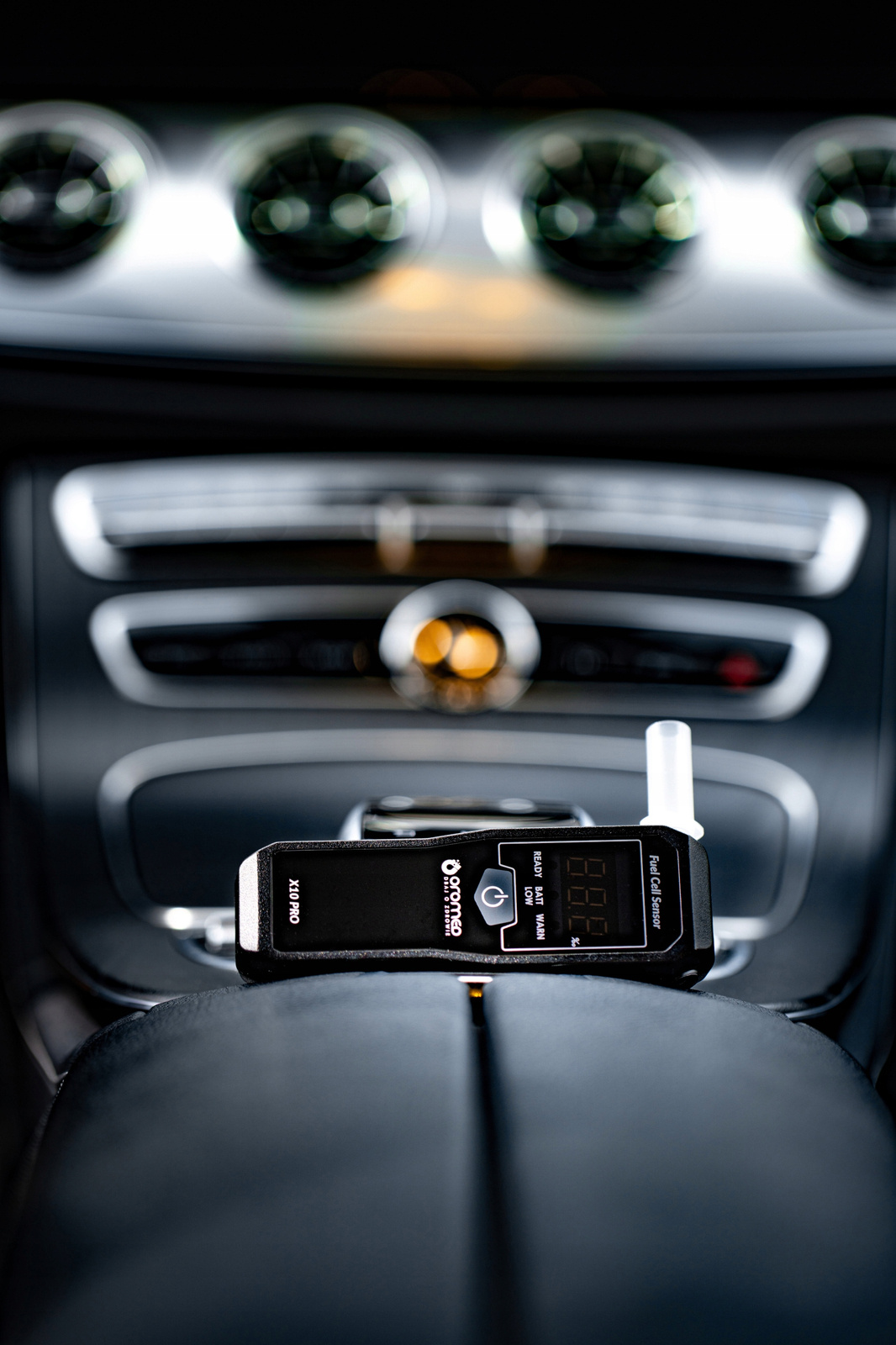 Alkomat wewnątrz samochodu z deską rozdzielczą i wnętrzem samochodu w tle.