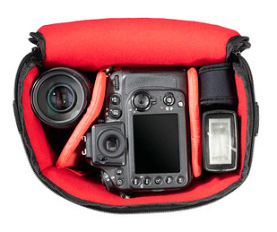 Torba na aparat z aparatem, obiektywem i akcesoriami w środku, na białym tle.