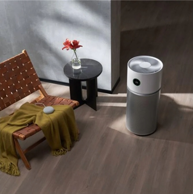 Oczyszczacz powietrza, krzesło, stół i kwiaty w pokoju.