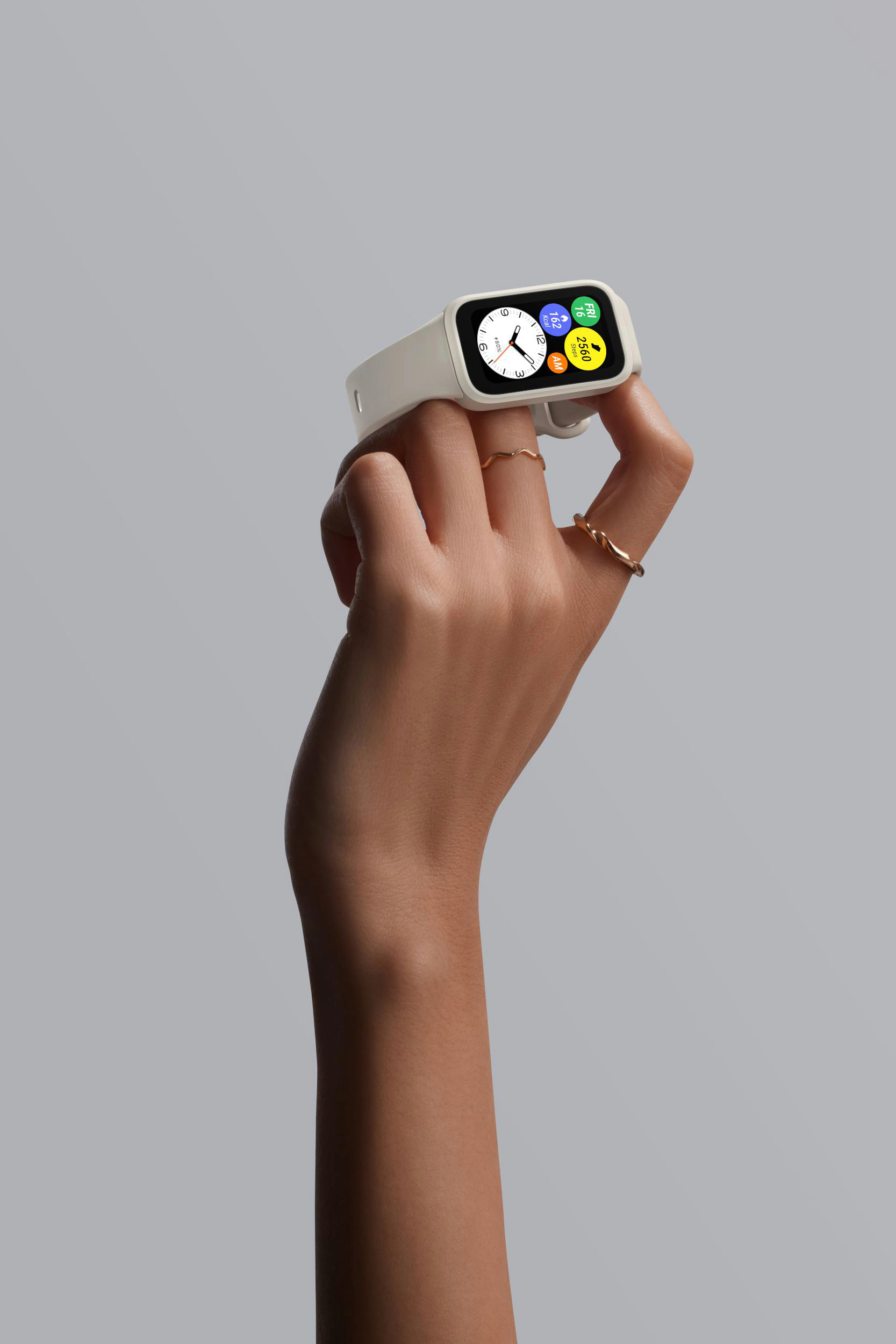Hand hält weiße Smartwatch mit farbigem Display, trägt Ringe.