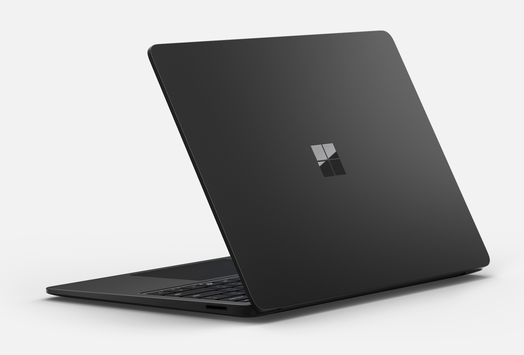 Czarny laptop z logo Microsoft na białym tle. Jest lekko otwarty.