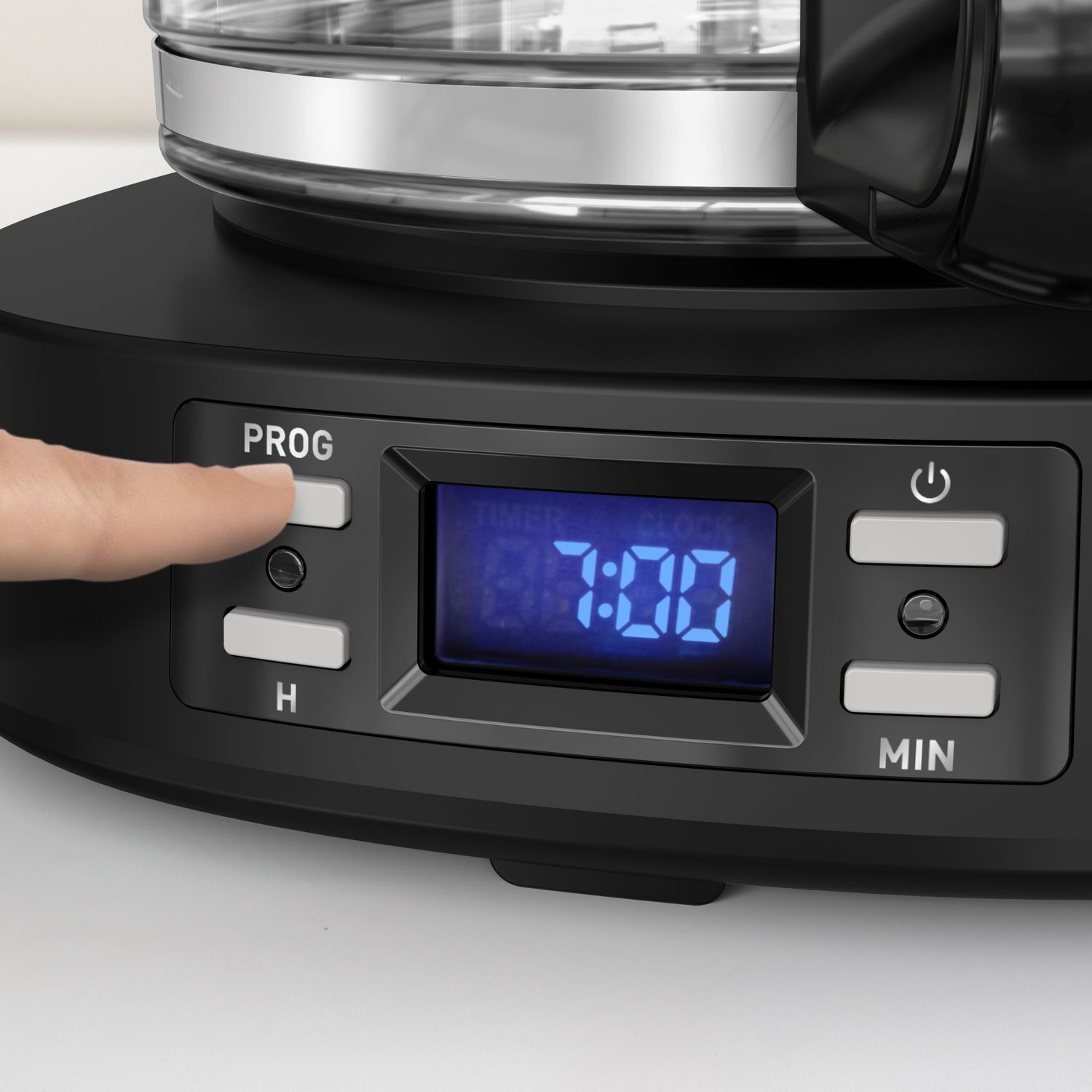 Close-up of a black coffee maker with a digital display showing 07:00, and a hand pressing a button.