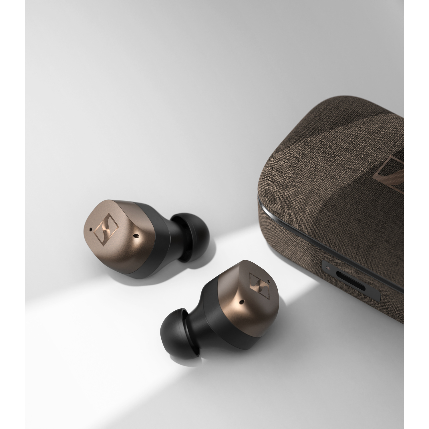 Sennheiser draadloze oordopjes en oplaadcase op een wit oppervlak.
