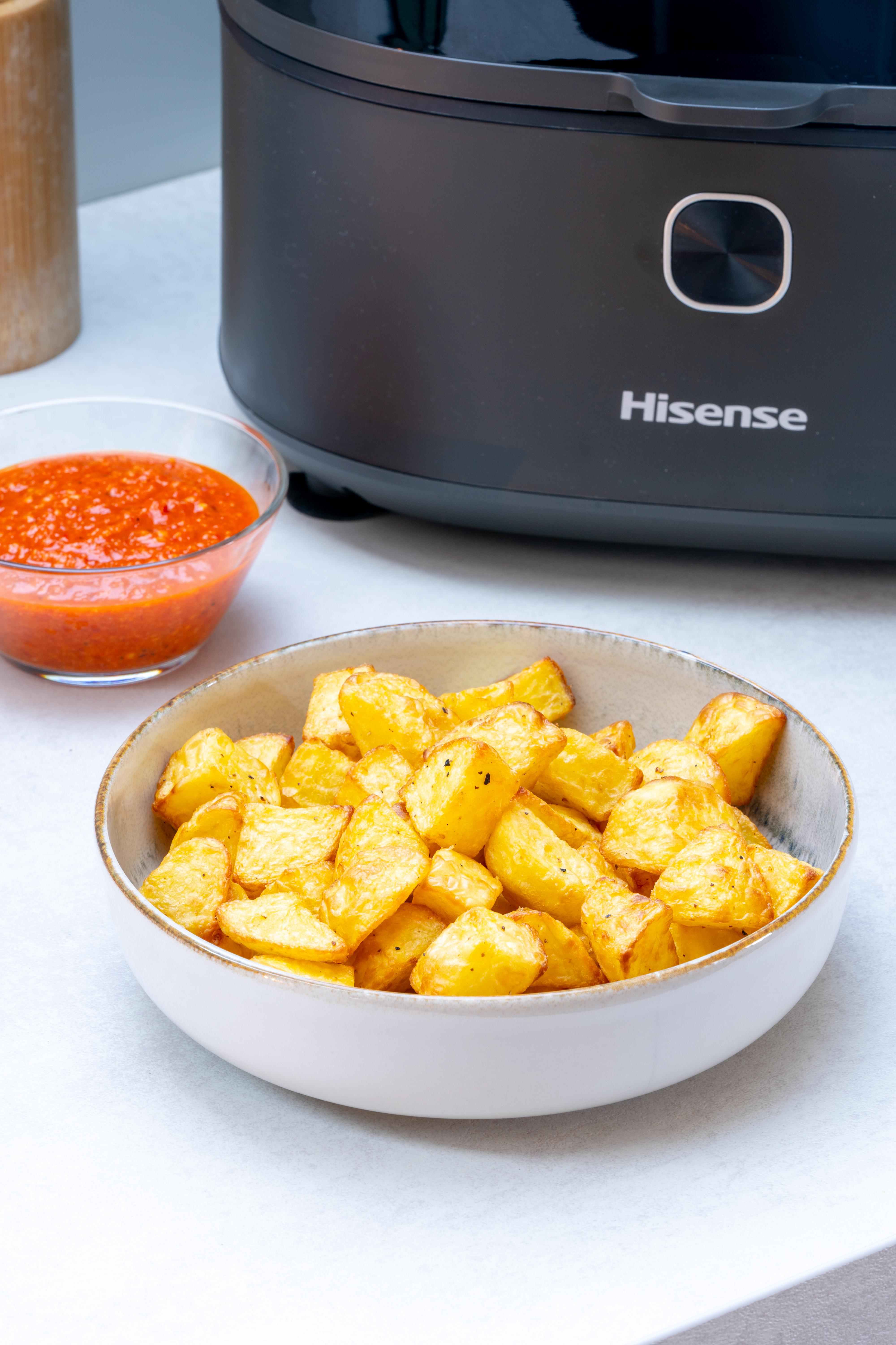 Schüssel mit Bratkartoffeln und Schüssel mit Soße neben schwarzer Heißluftfritteuse.